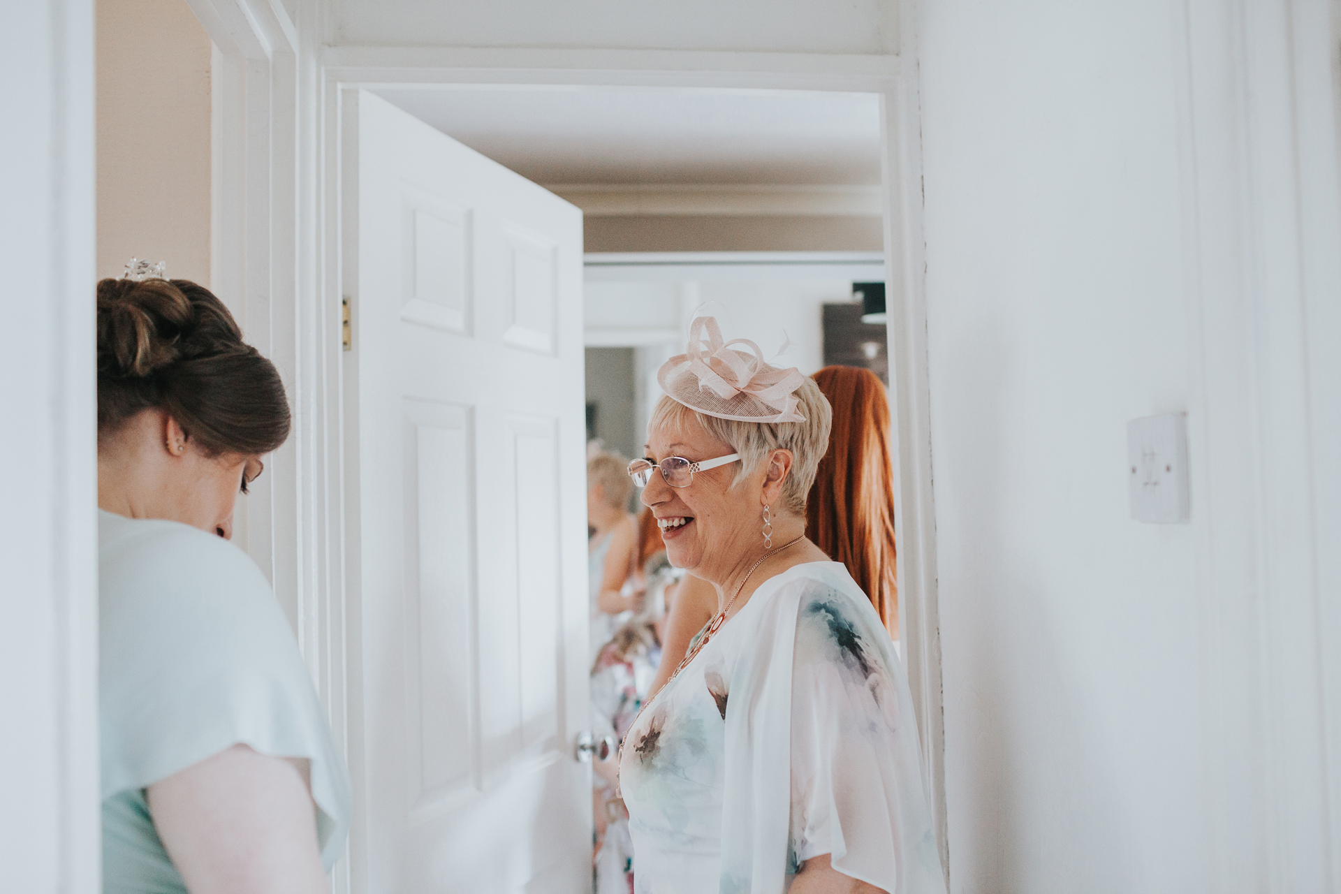 Mother of the bride looks excited waiting for her daughter in the hallway. 