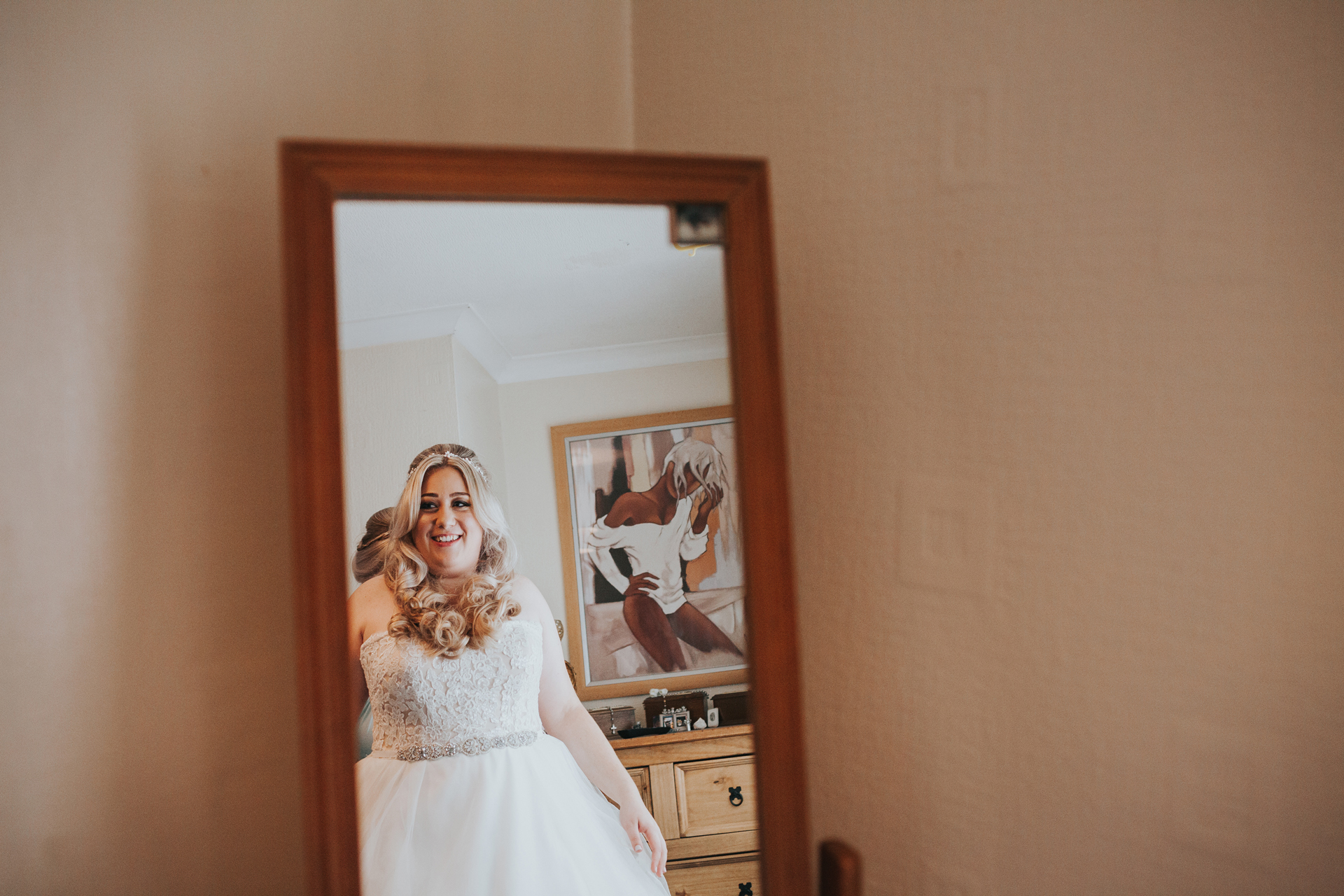 Brides reflection in the mirror as she wears her wedding dress. 