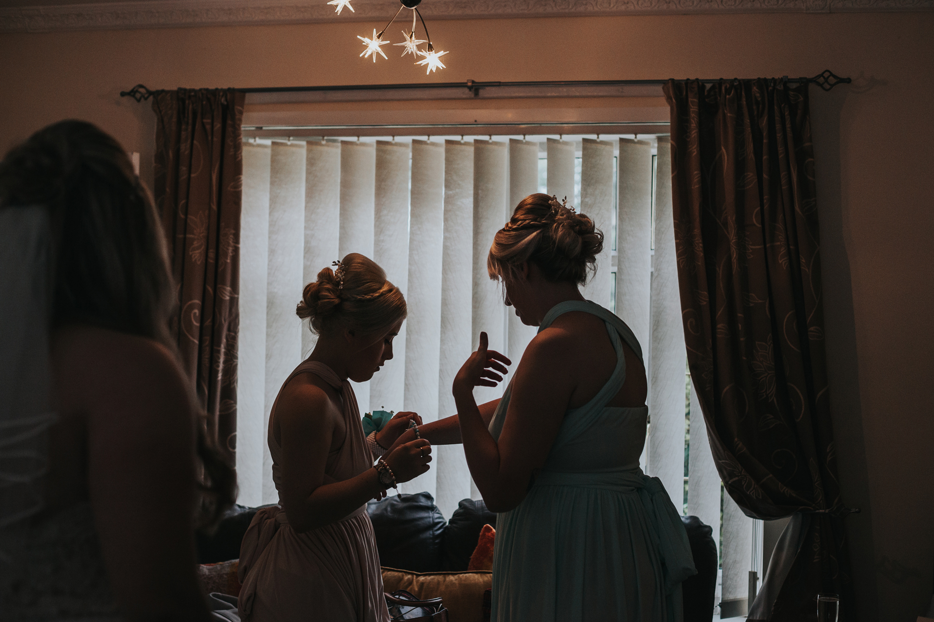 Silhouette of bridesmaids getting ready in front on the window. 