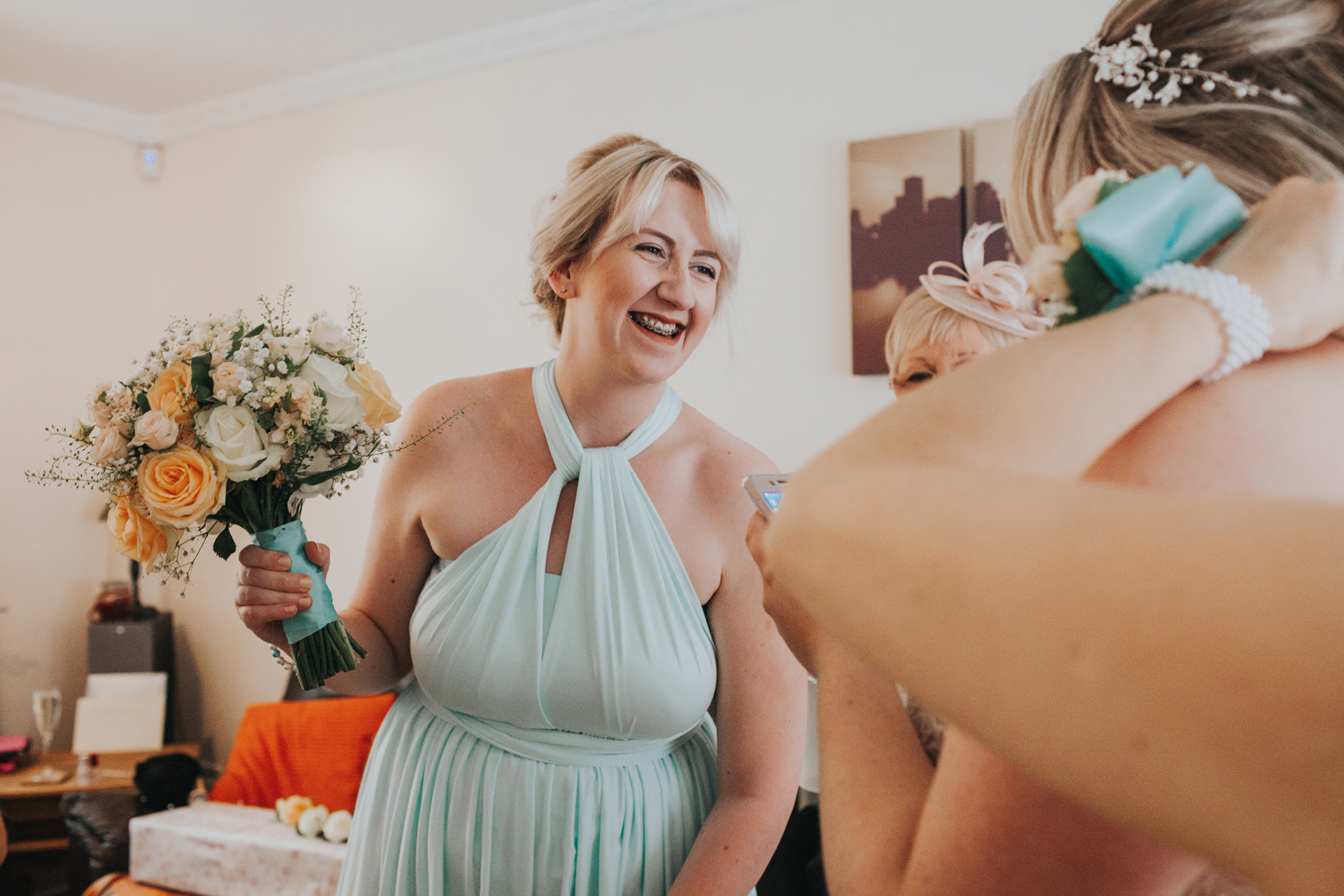 Bridesmaid leans forward laughing holding her flowers. 