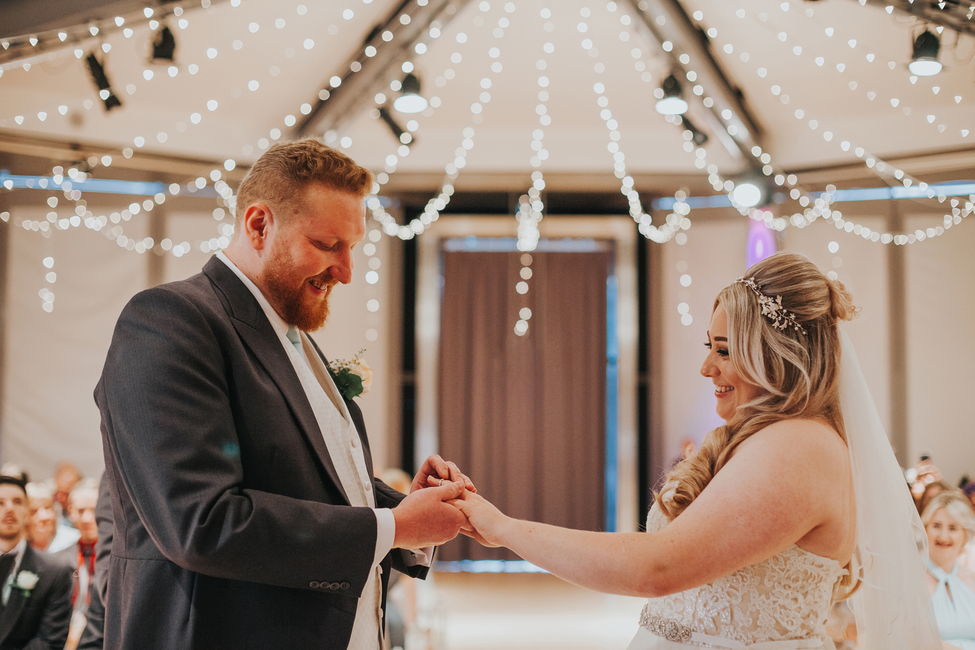 Groom places brides ring on her finger. 