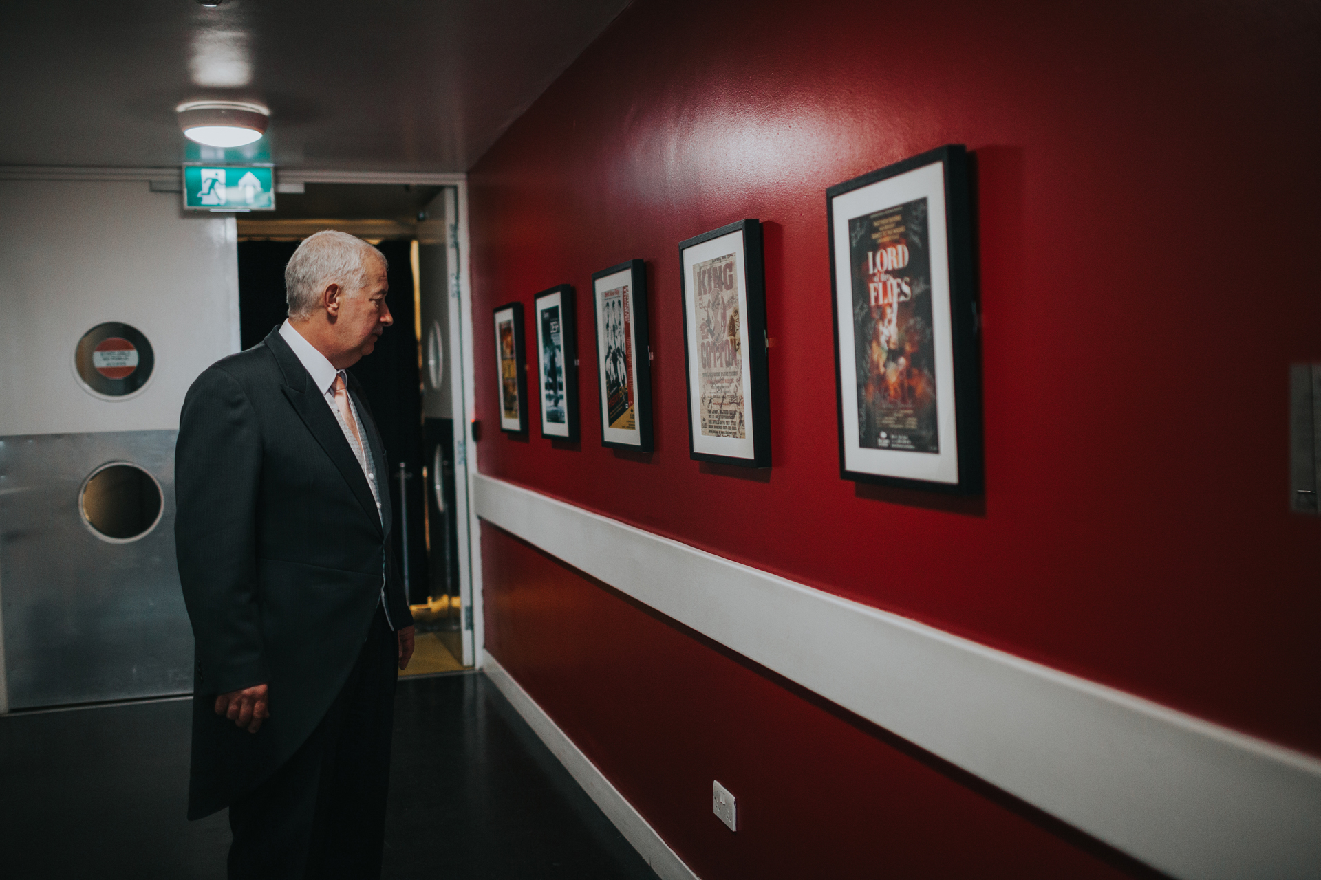 Wedding guest appreciates artwork in hall way. 