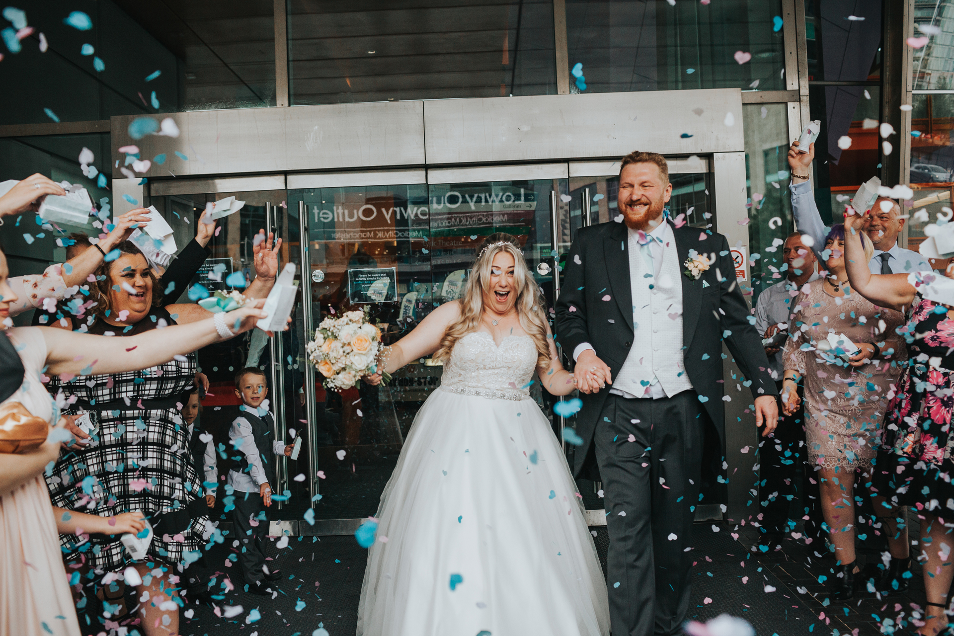 Bride and Groom exit the Lowry Theatre to have confetti thrown at them by wedding guests. 