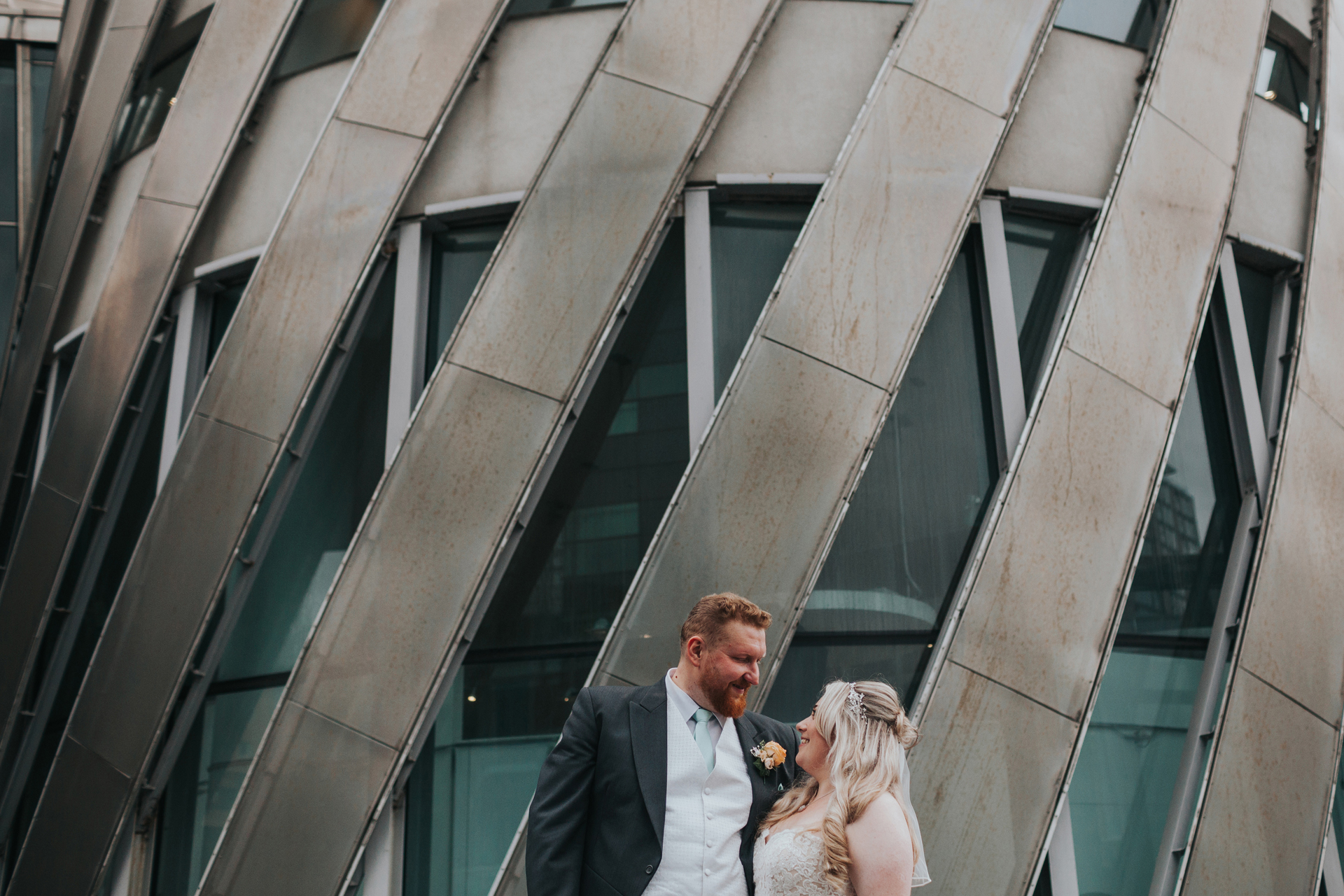 Bride and Groom stand together in front of metal wall.  