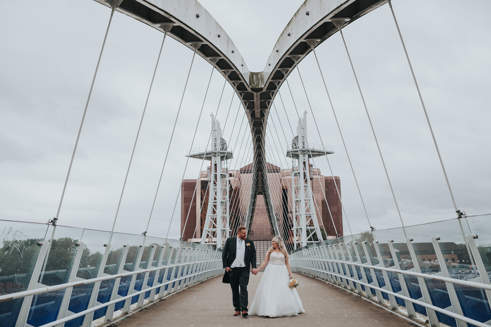 Bride and groom walk down the bridge together. 