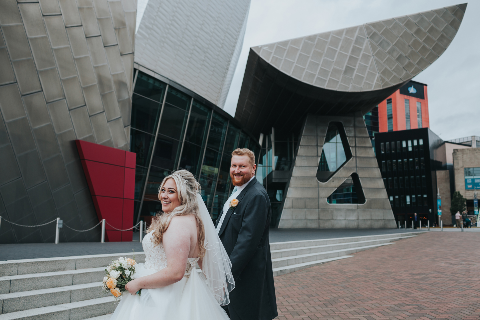 Bride and Groom stand in front on The Lowry Theatre. 