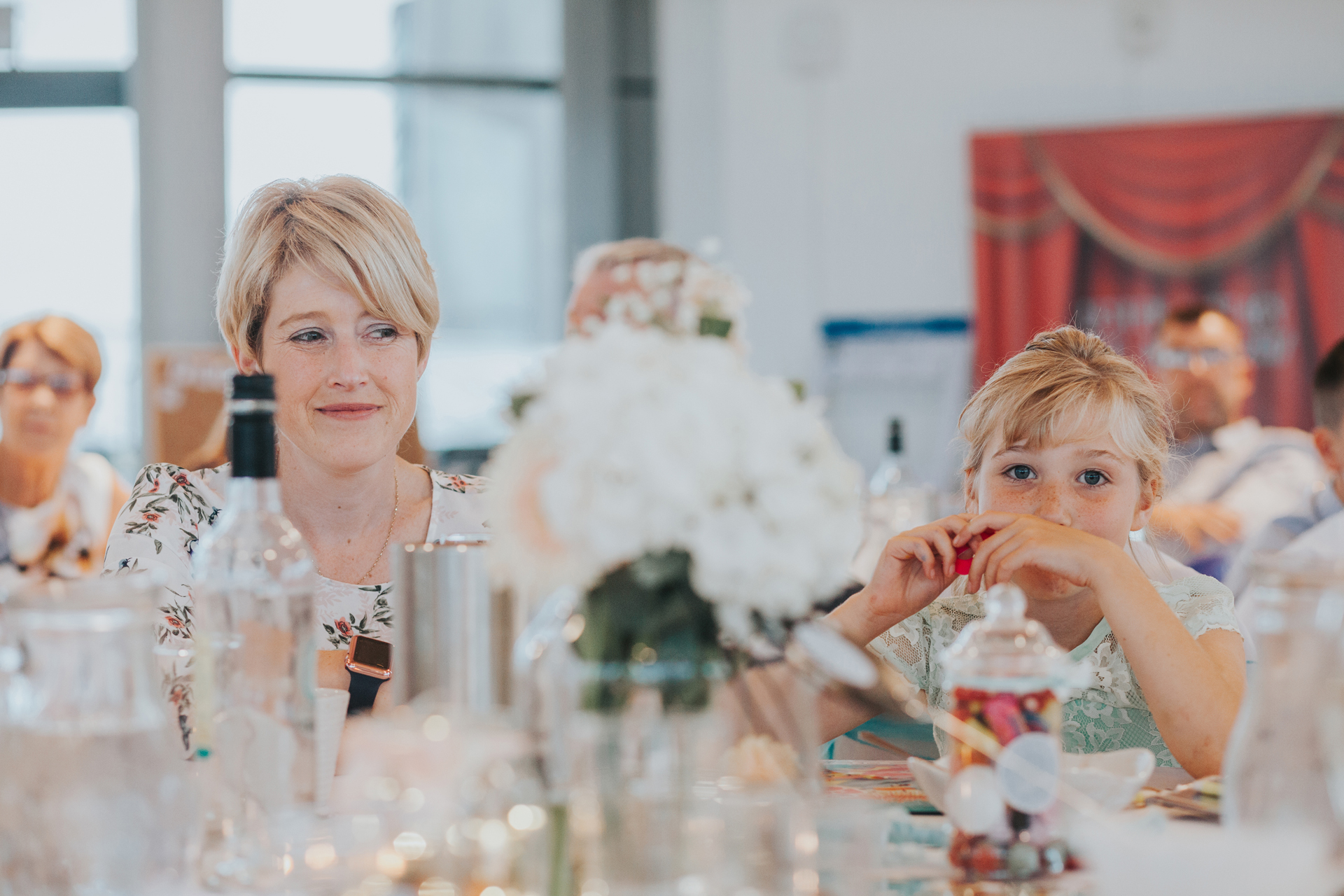 Flower girl eats sweets at wedding table. 