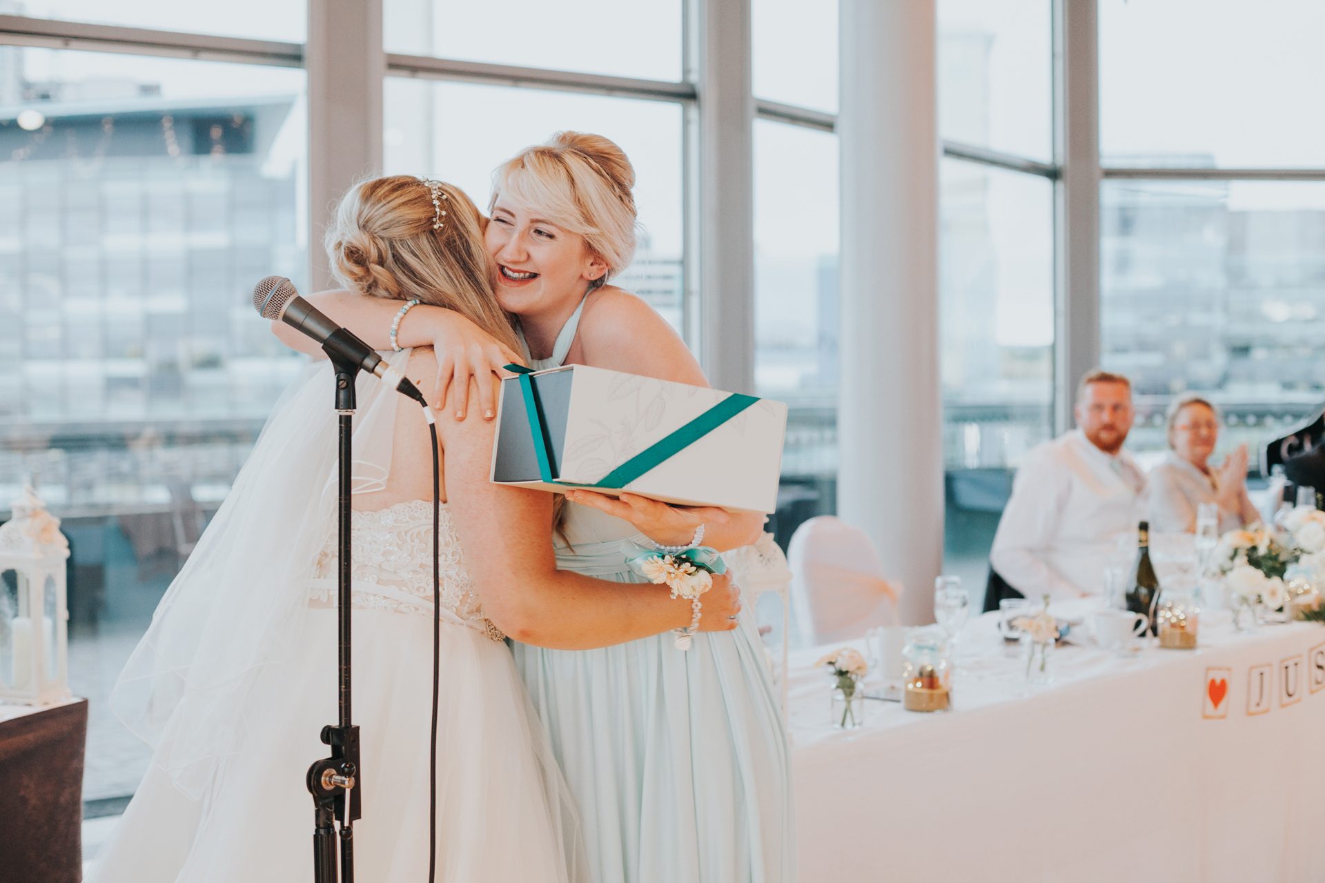 Bridesmaid gives bride a big hug.