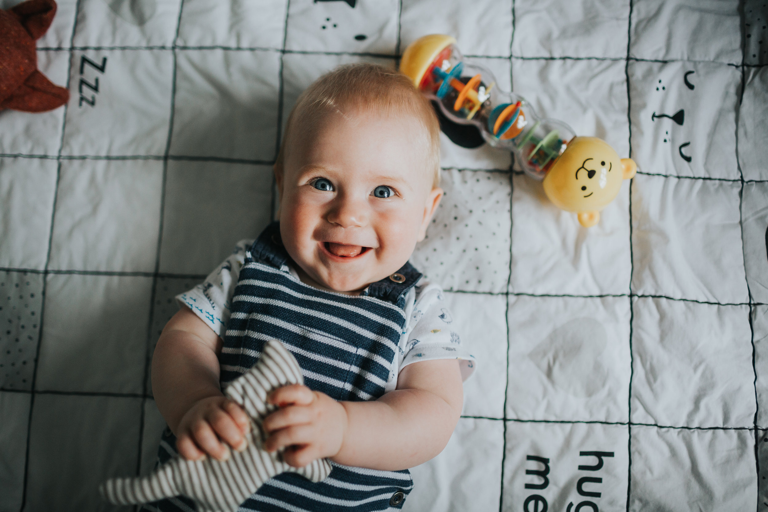 Baby giving the camera a big smile, holding his toy.