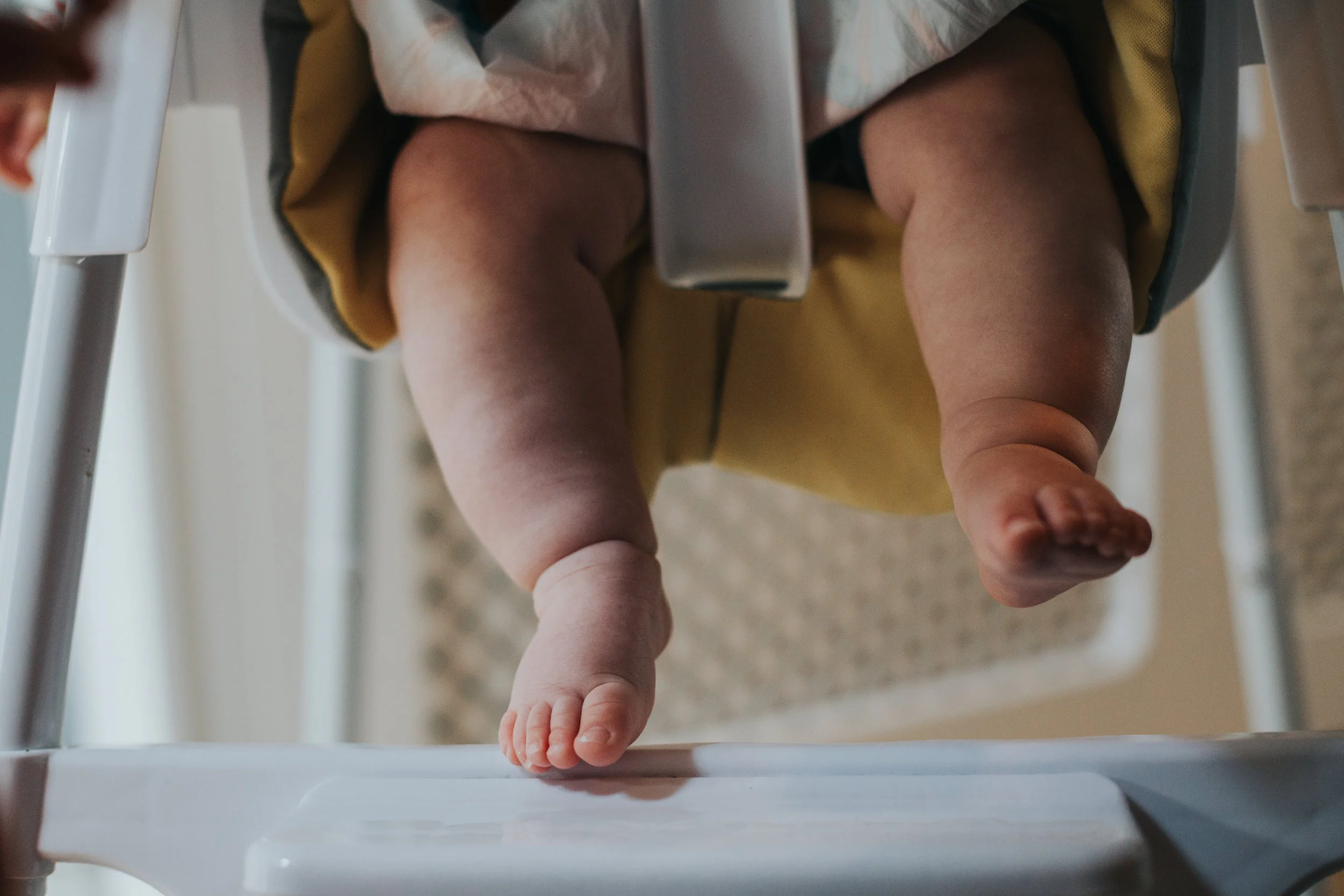 Close up of babies feet in high chair. 