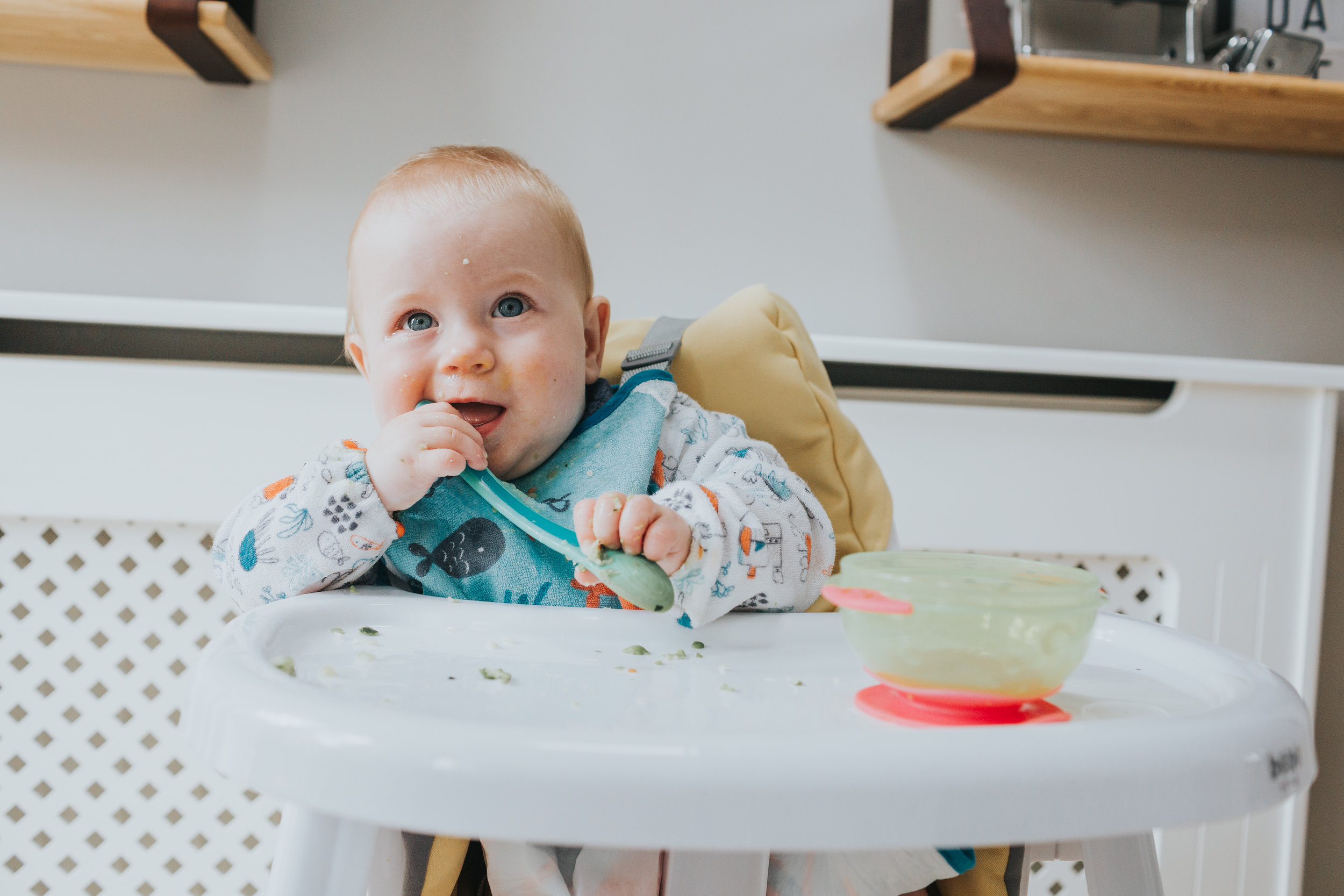Baby smiles while holding spoon in her mouth. 