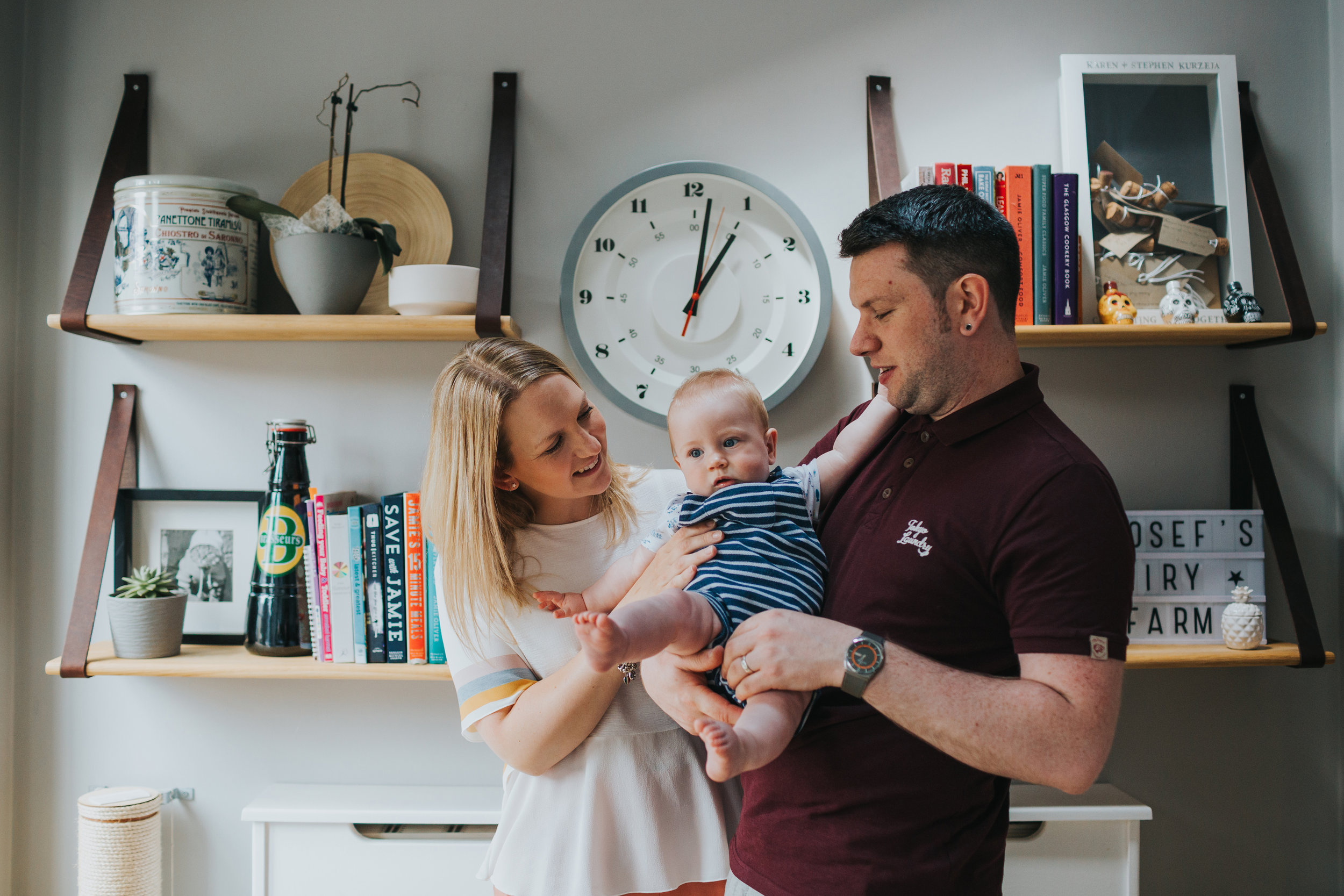 Mum, Dad and Baby stand together in kitchen. 