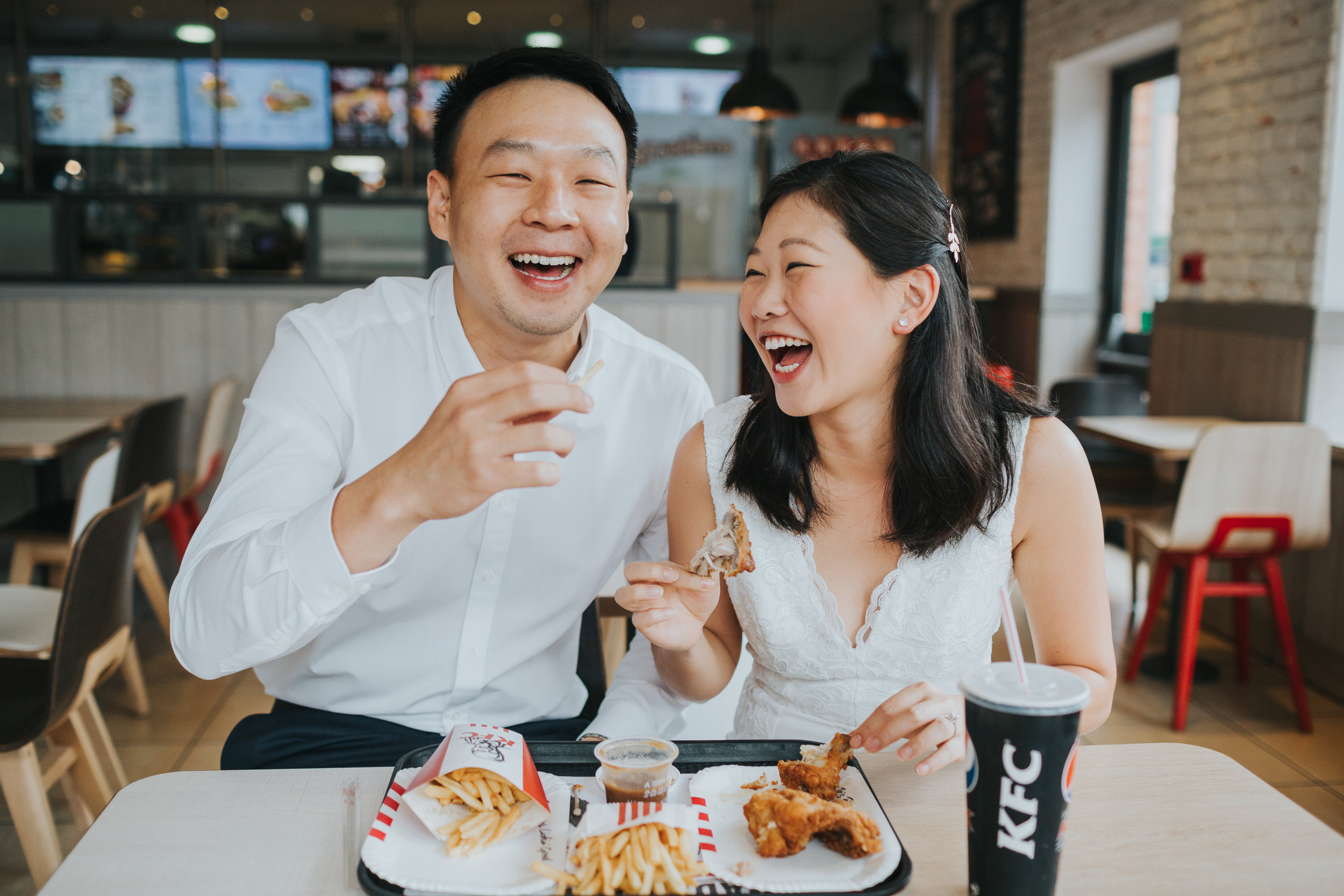 Couple laugh while eating chicken in KFC. 