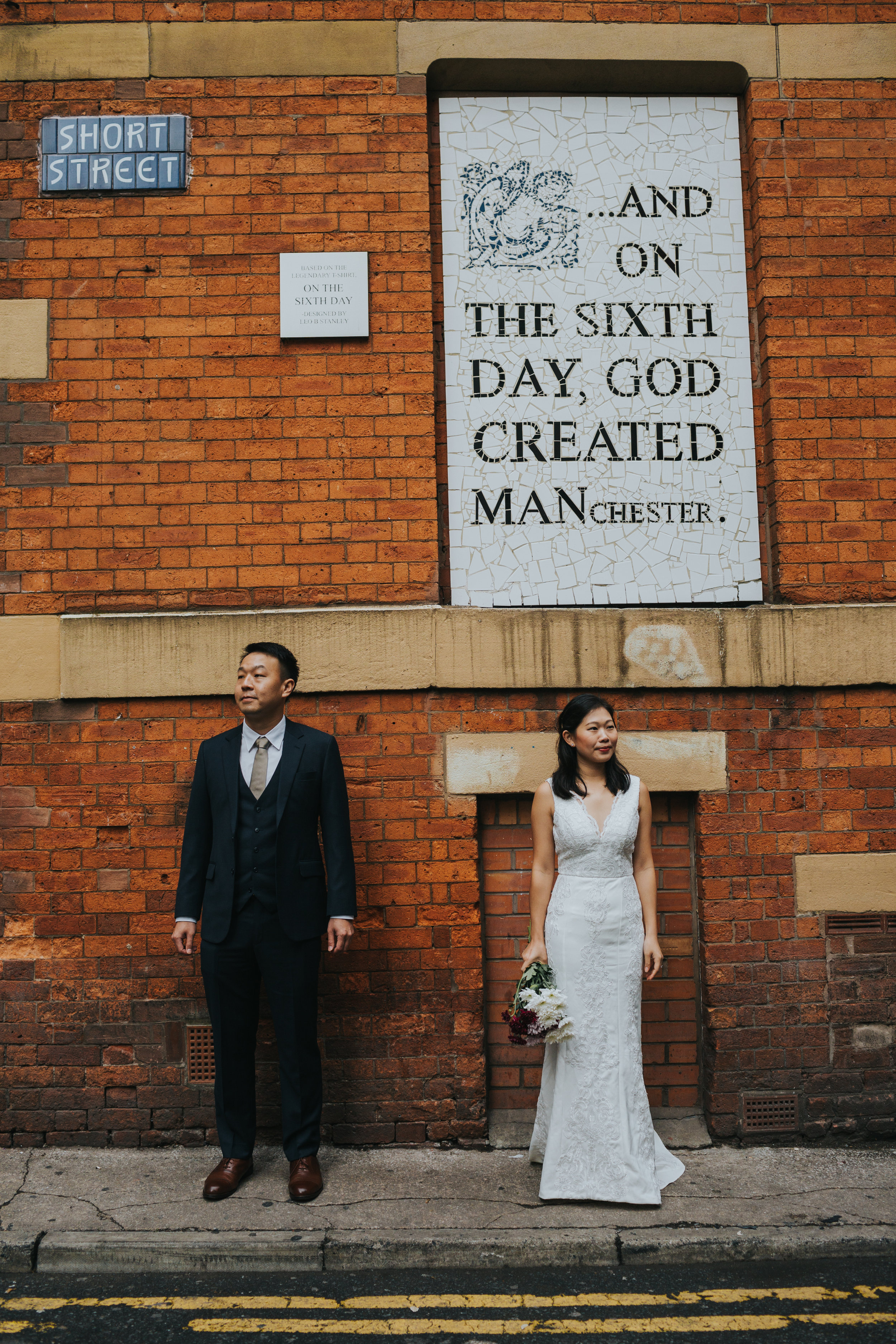 Couple stand together in Wedding gear in front of Aflecks Palace, Manchester.