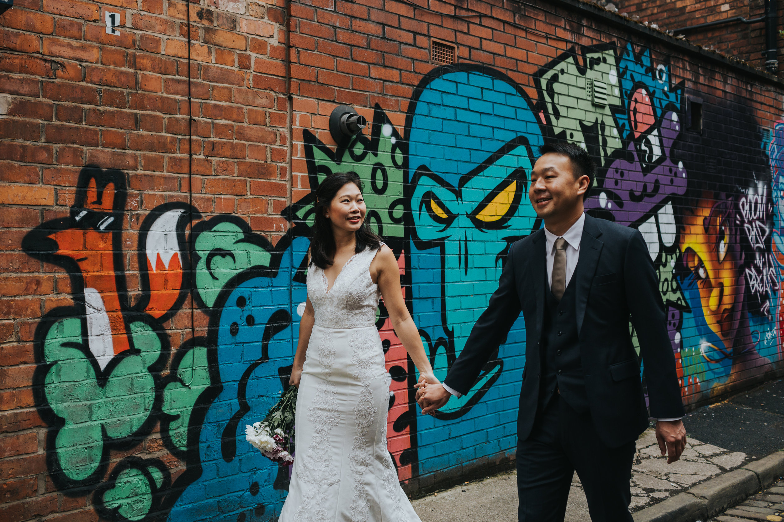 Couple holding hands and walking together in Northern Quarter alley, Manchester. 