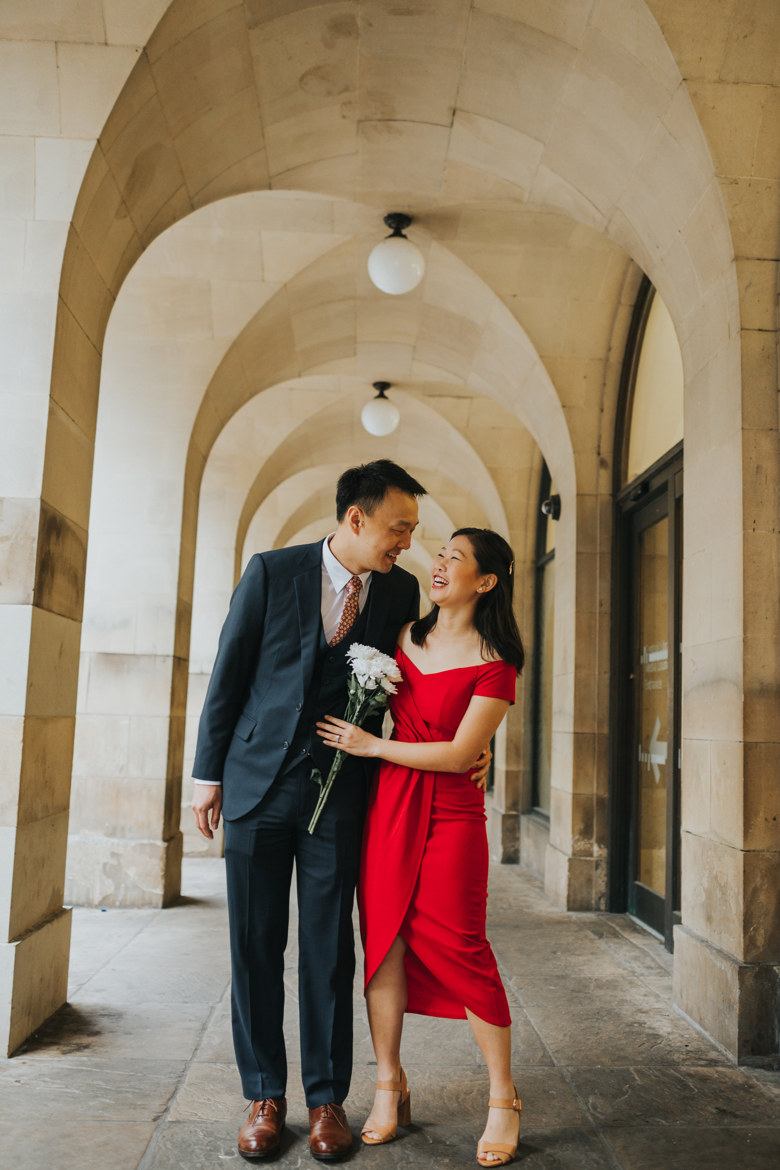 Couple laugh together in the archways of Manchester Town Hall. 