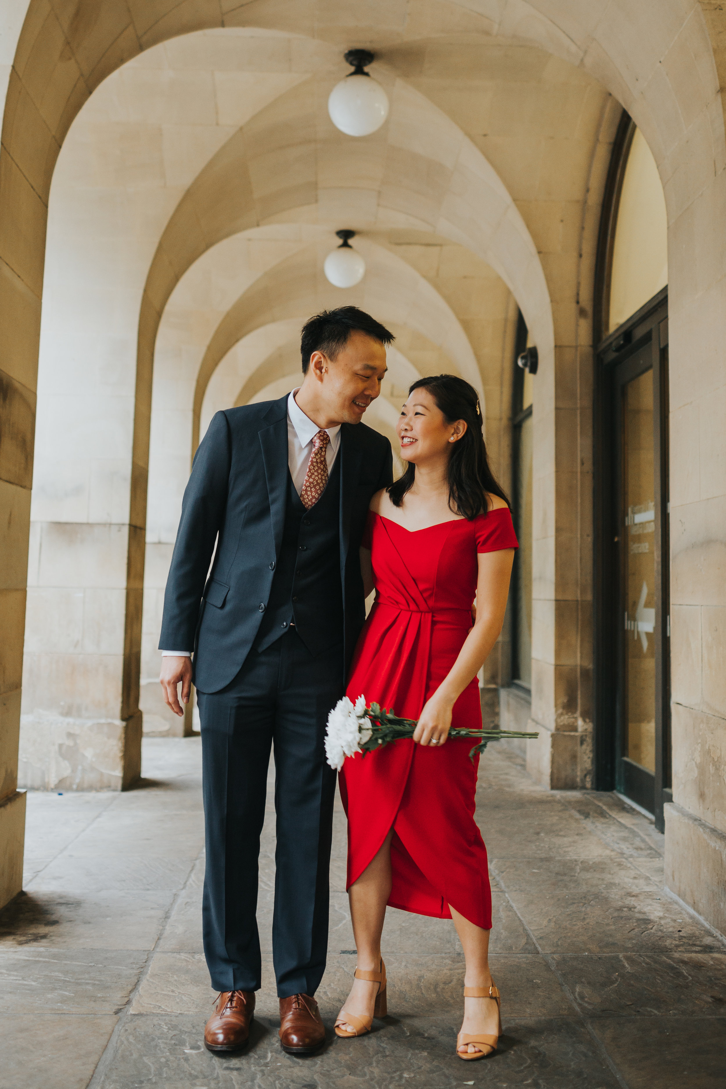 Couple smiling under the Manchester Town Hall Archways.