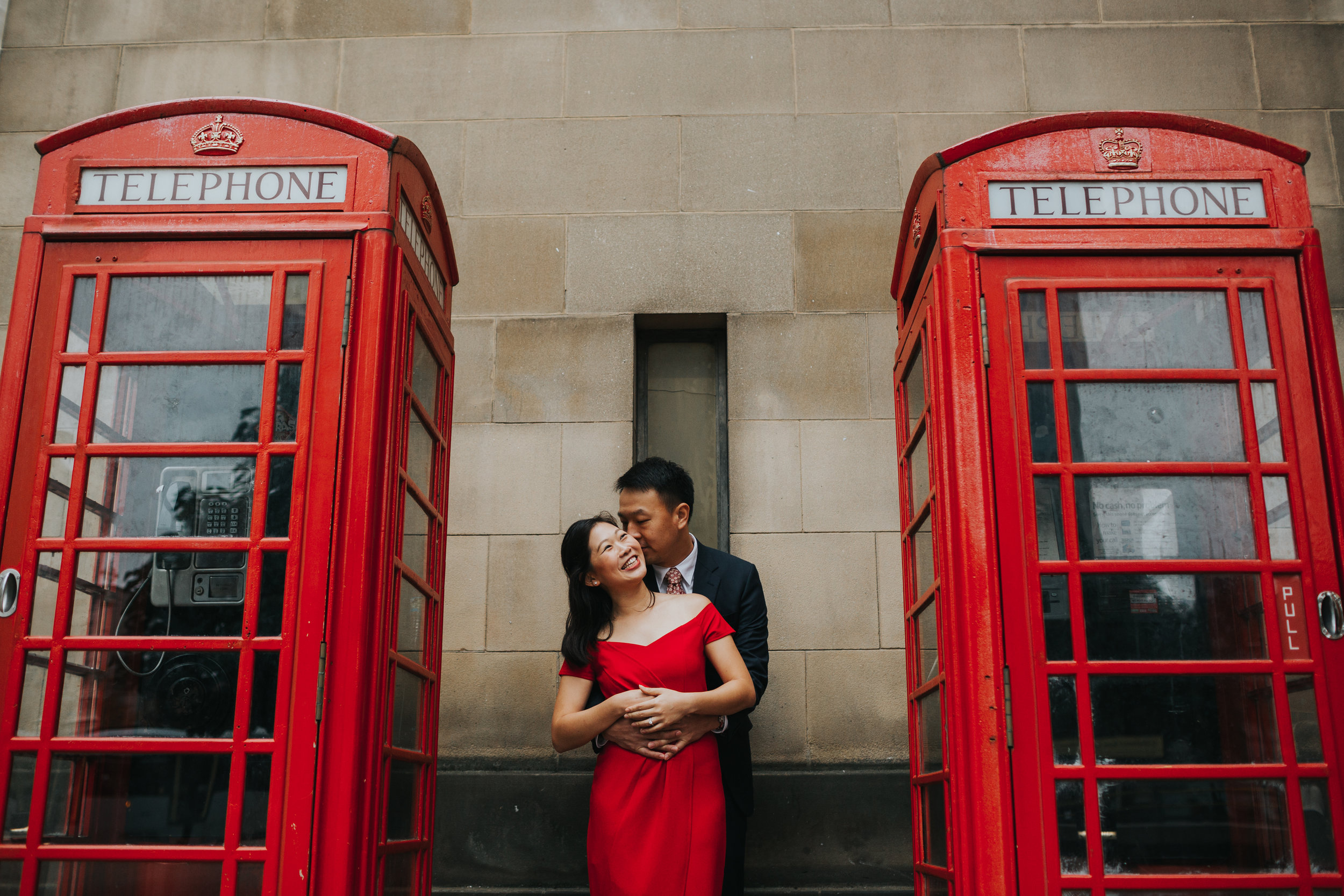 Couple in between two red phone boxes in Manchester. 