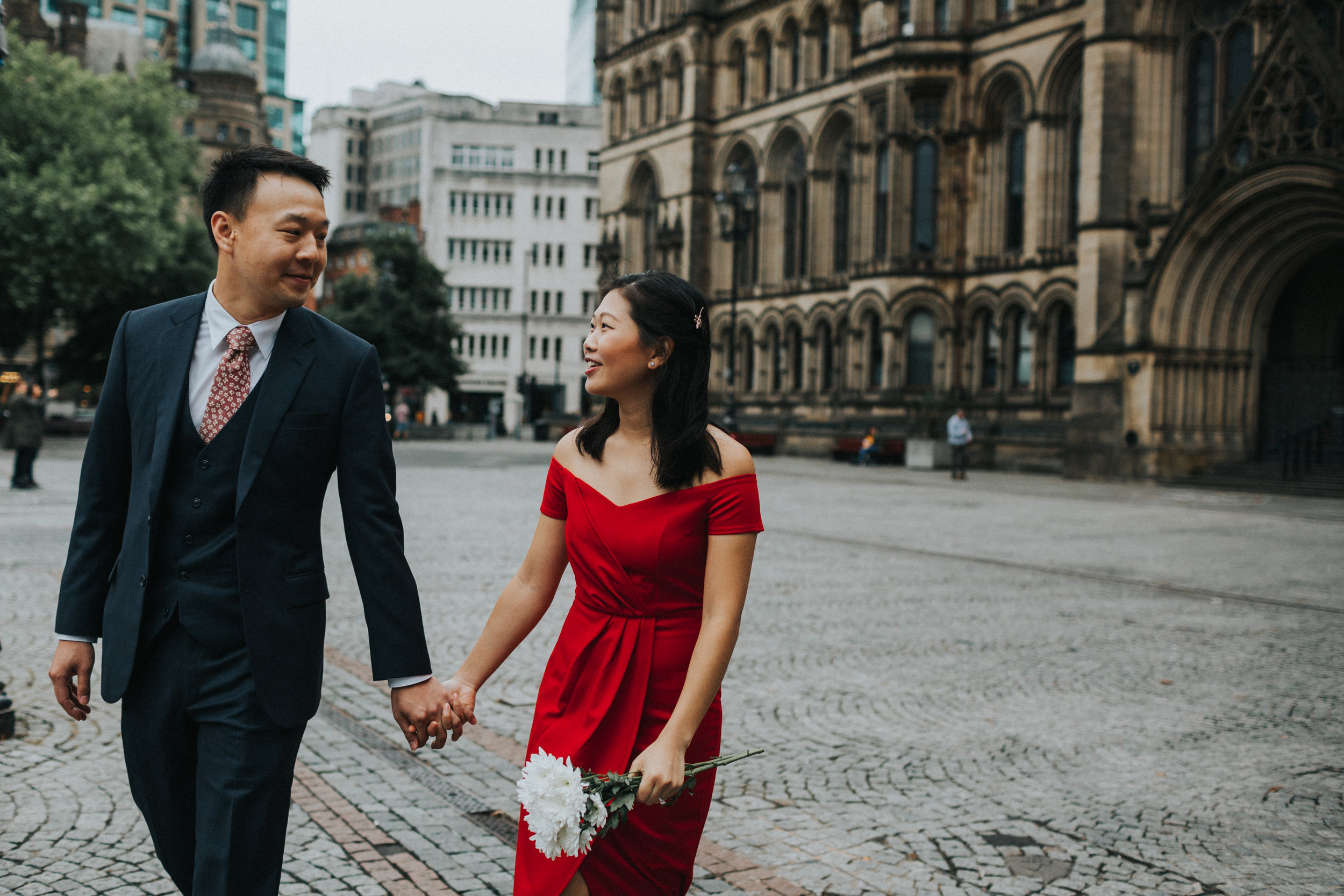 Couple walking together in front of Manchester Town Hall. 