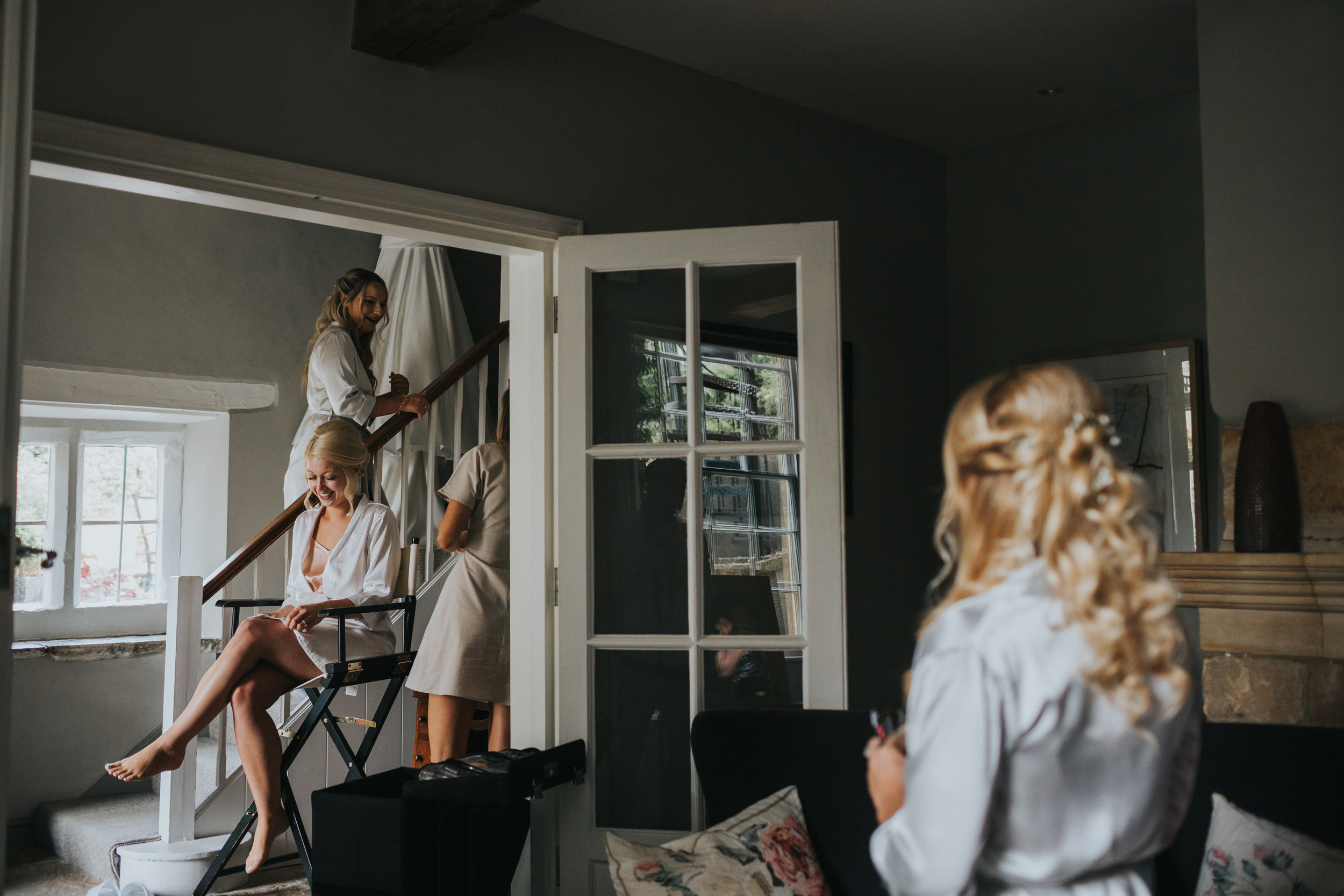 Bride getting ready in the hall as bridesmaid watches from the sitting room. (Copy)