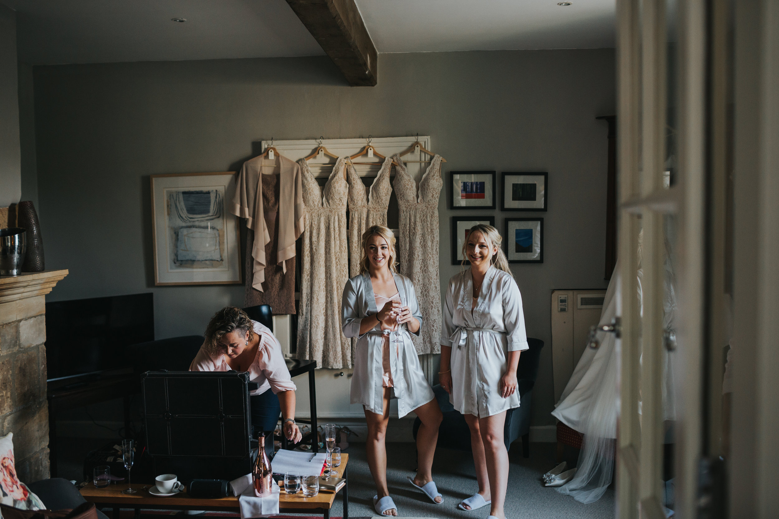 Bridesmaids watching bride getting ready smiling.