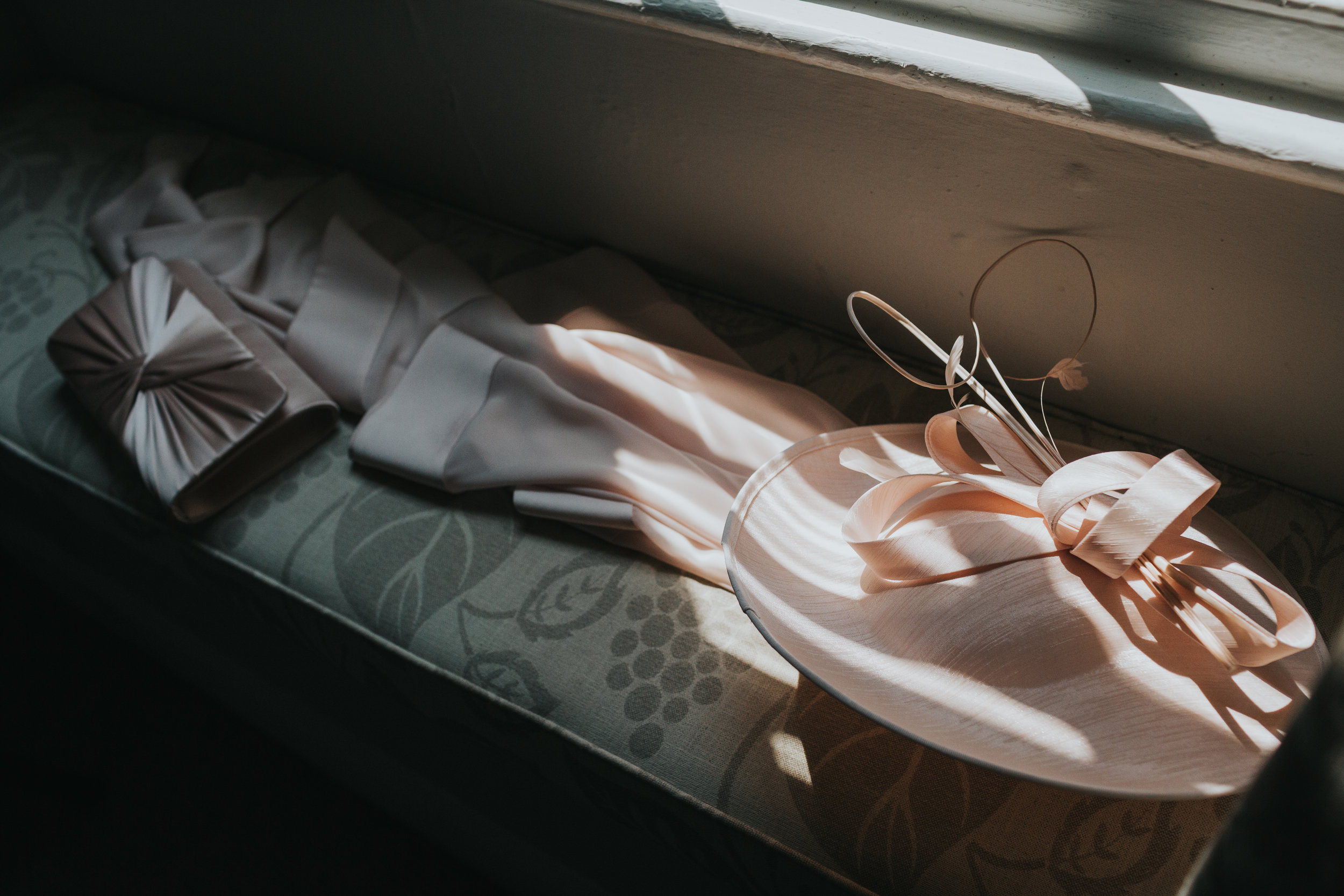 Mother of the brides hat, jacket and purse in some speckled window light.