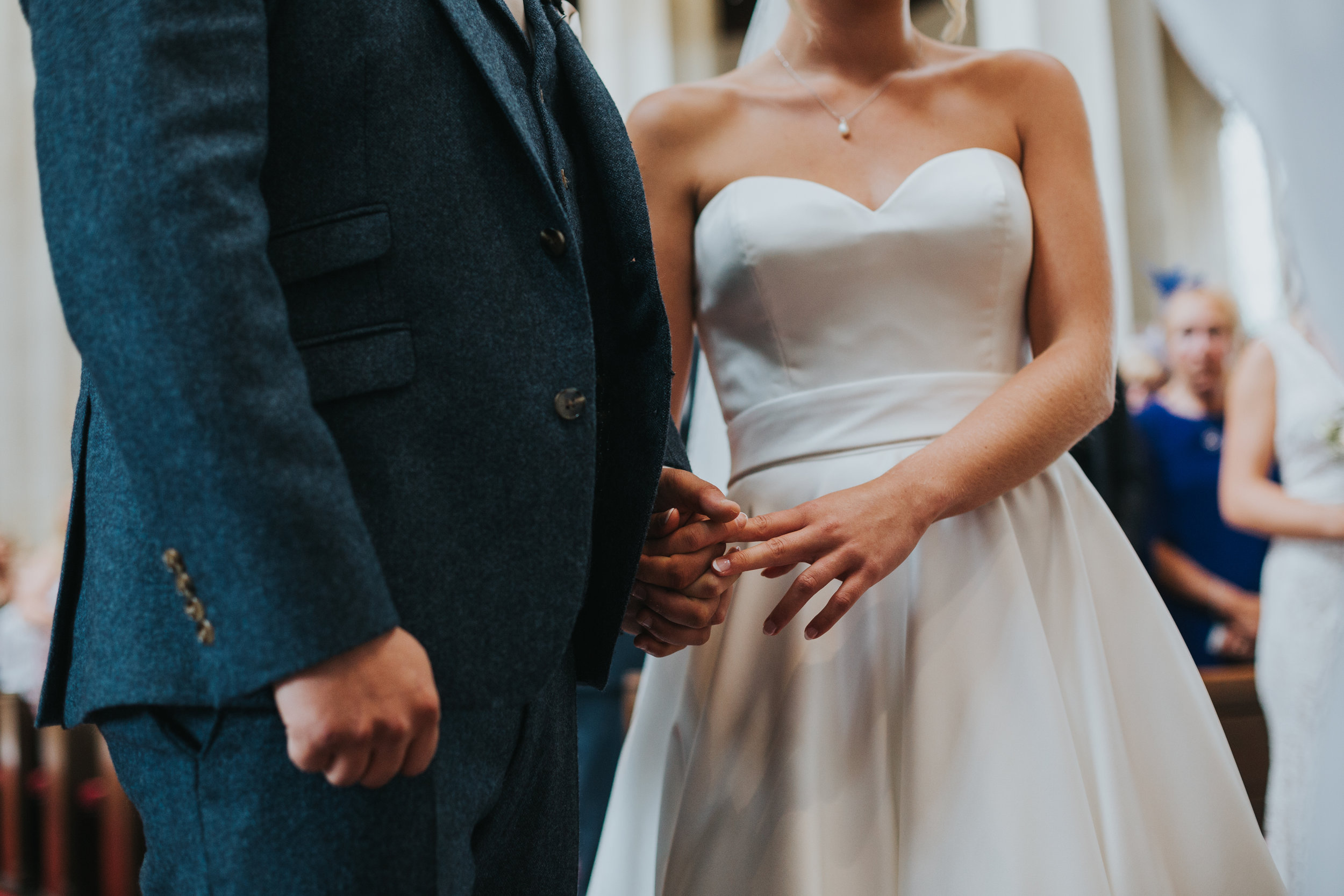 Close up of the brides dress and the grooms suit as they stand together.