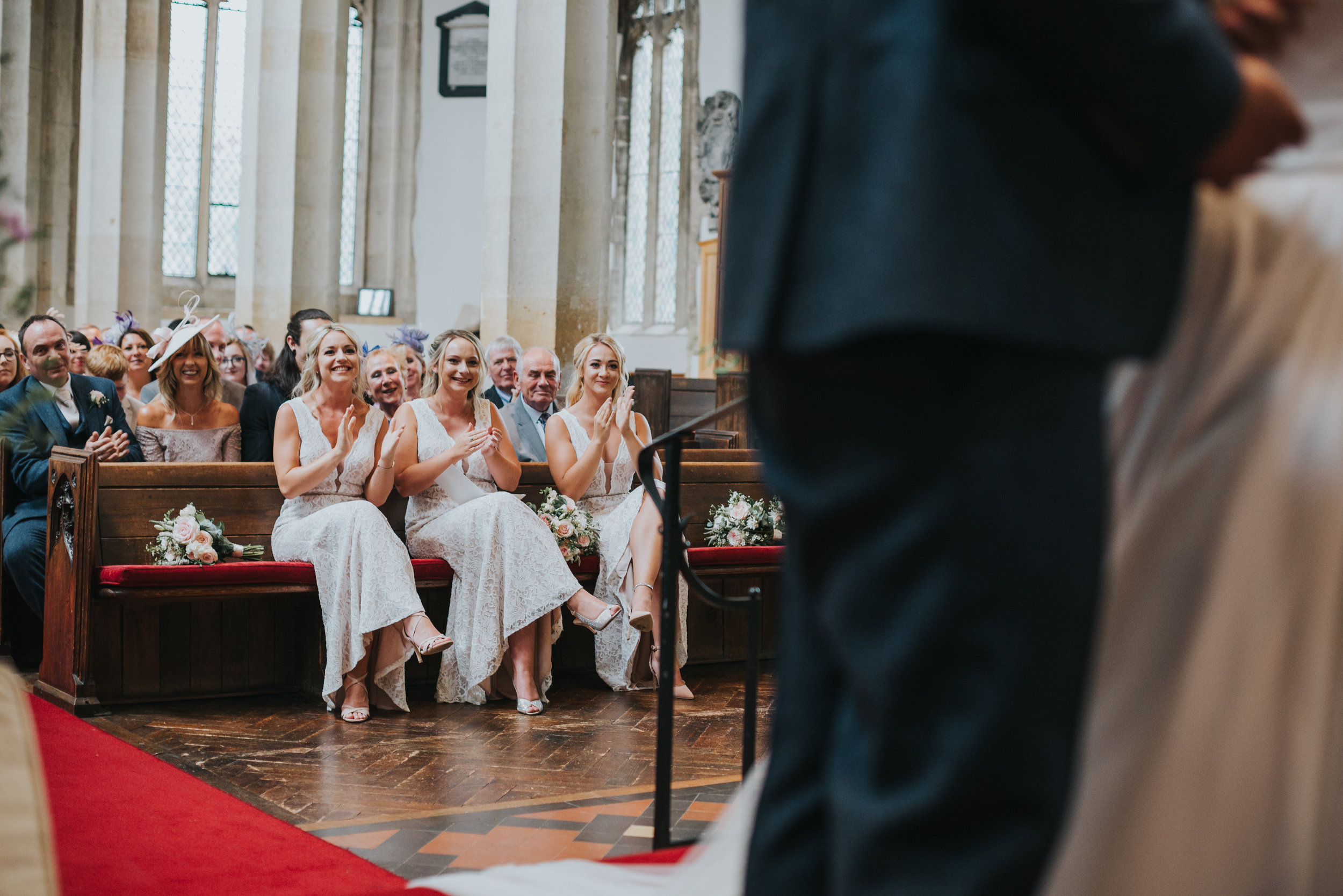 Bridesmaids clapping as bride and groom kiss in foreground.  (Copy)