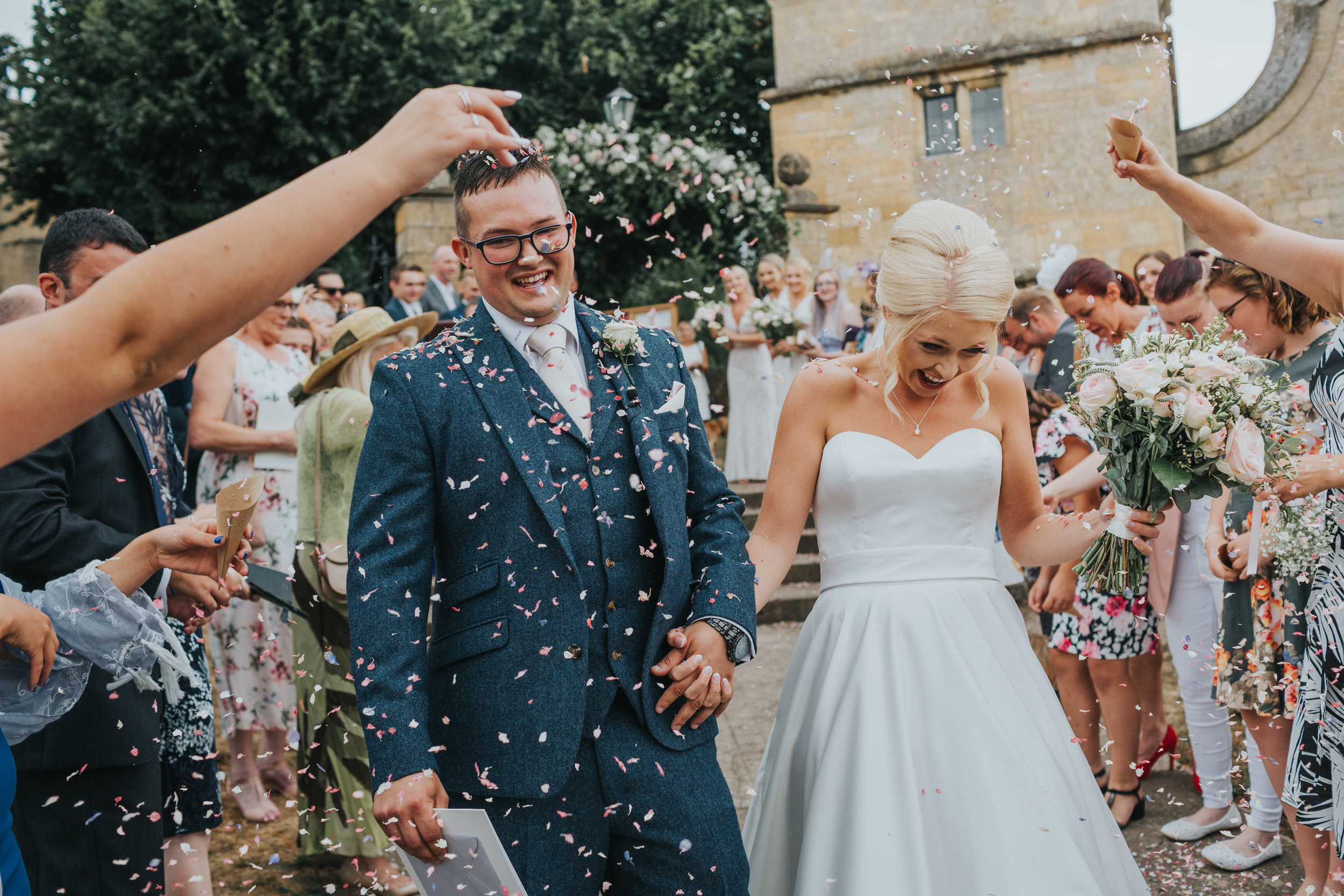 Bride and Groom laugh as they have confetti thrown out them outside St James Church, Chipping, Campden.  (Copy)