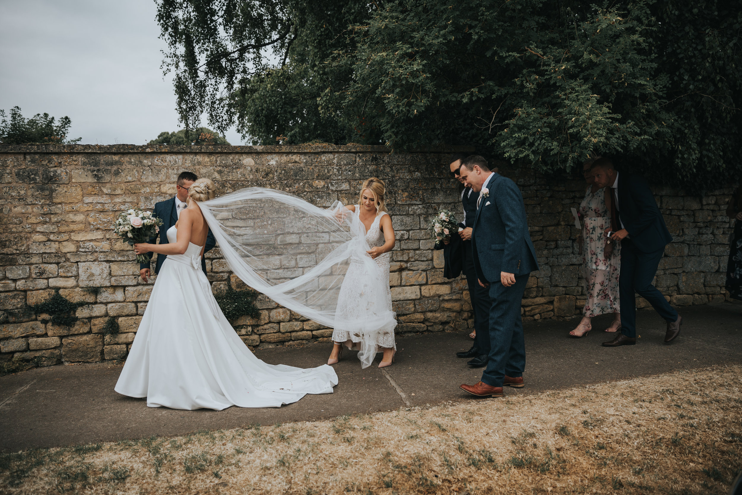 The sister of the bride helps her with her veil.  (Copy)