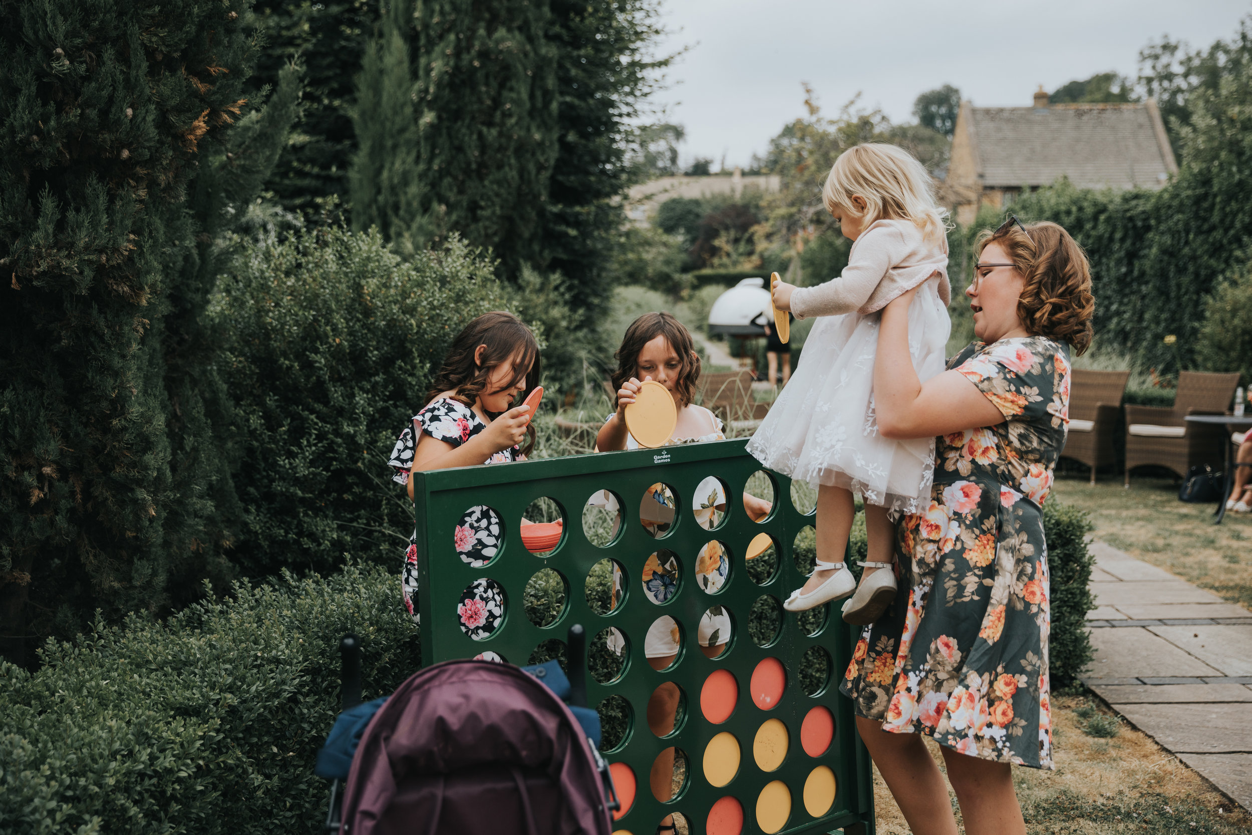 Little girl is picked up so she can play Connect 4 with her two taller friends.  (Copy)