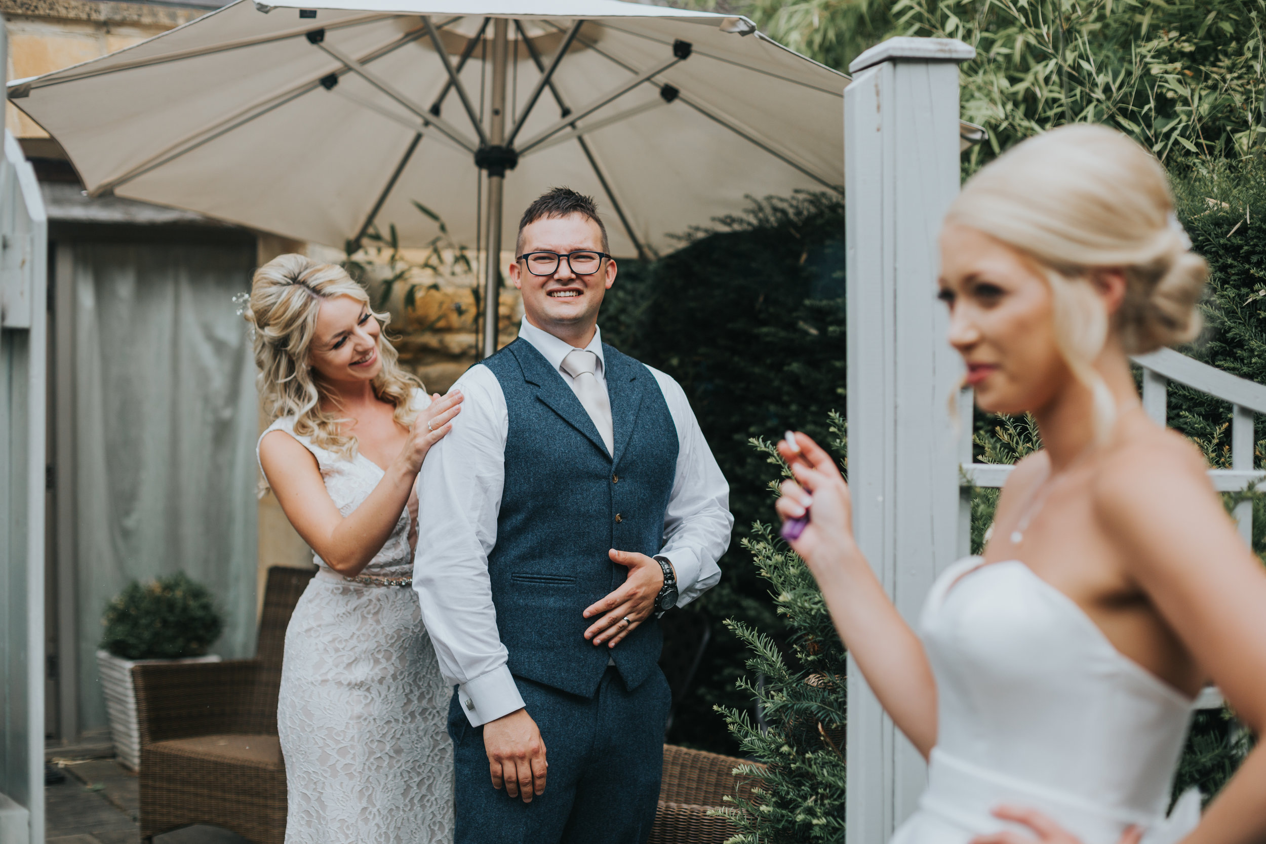 Bridesmaid fixing grooms suit as bride has a fag.  (Copy)