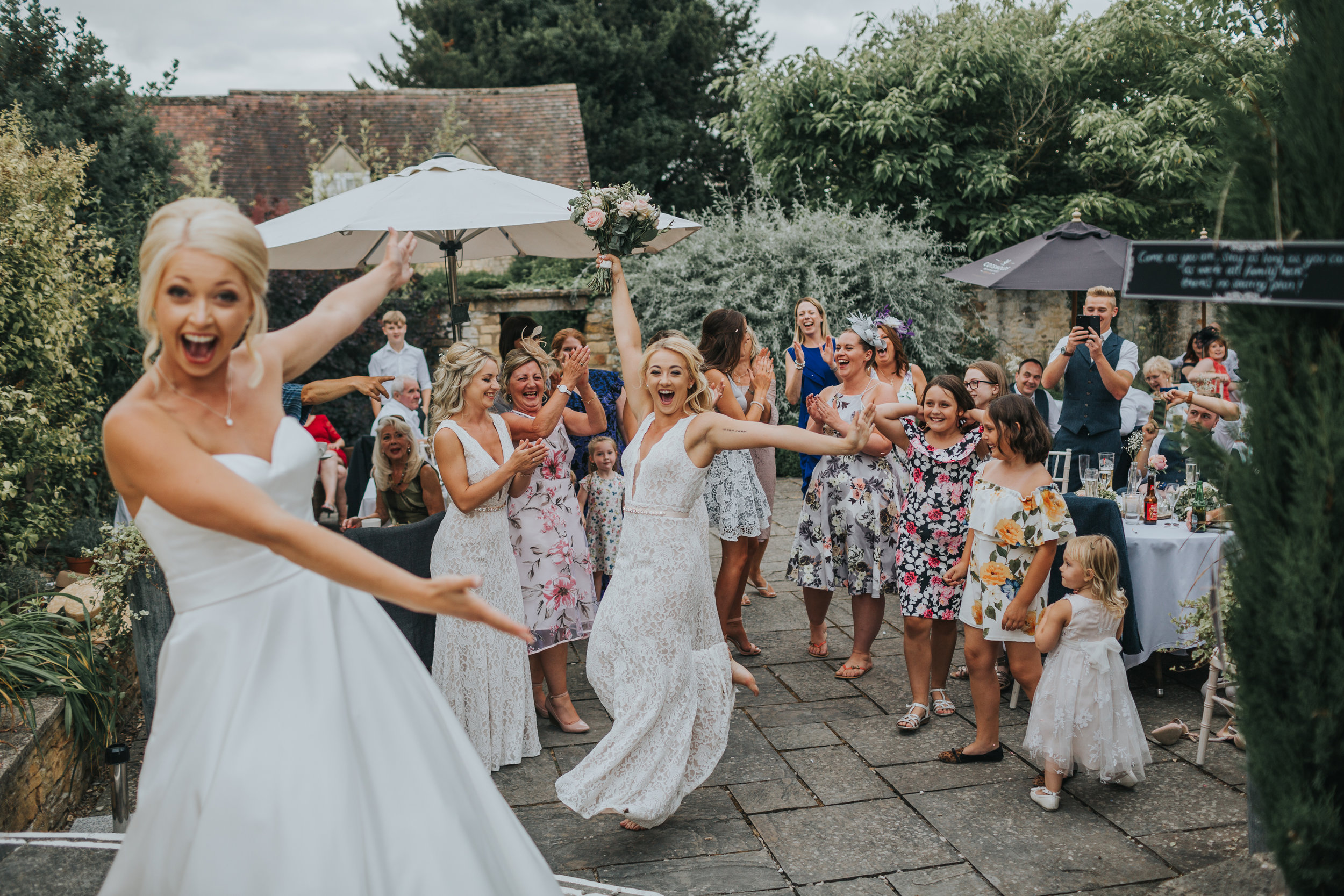 Sister is doing a victory dance with the bouquet as the Bride points at her laughing.  (Copy)