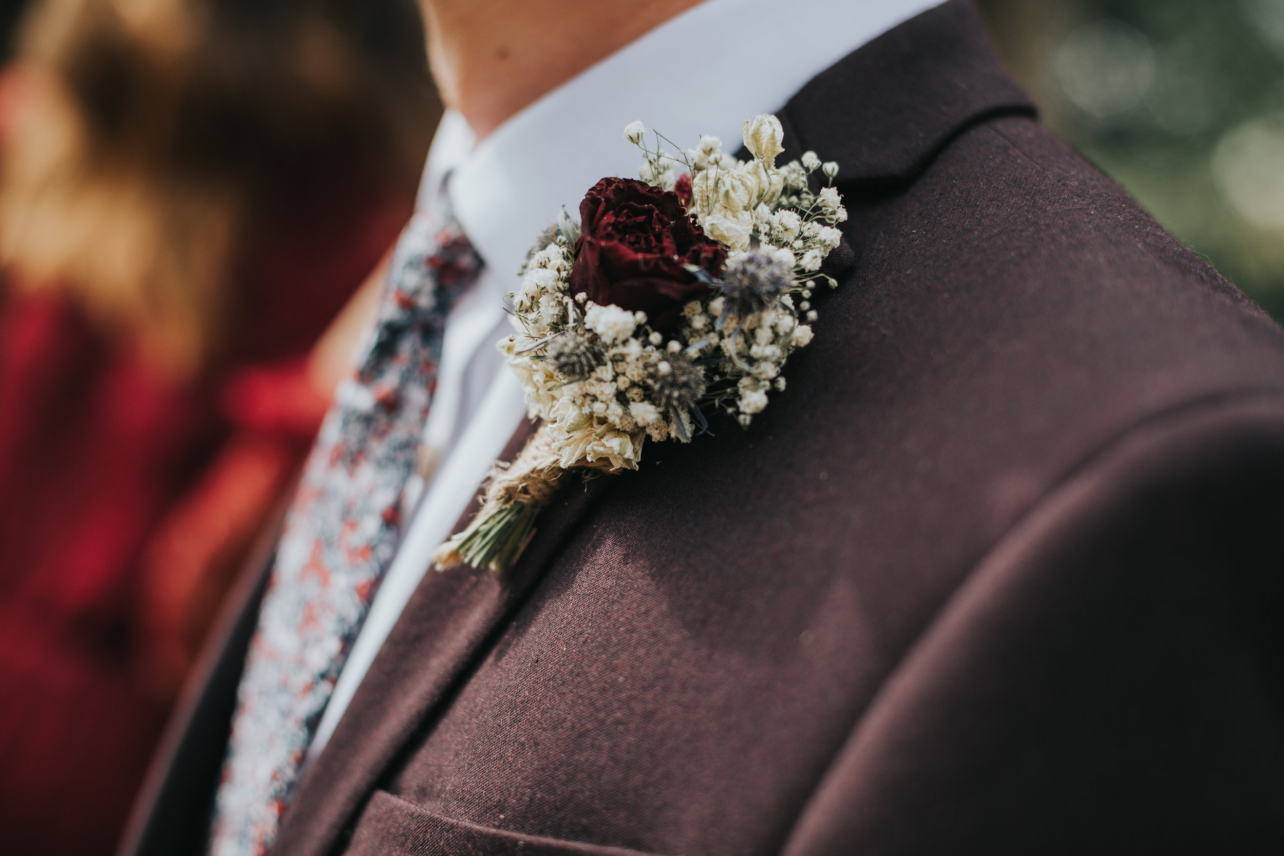Dried flower button hole, featuring a red rose and gypsy grass.