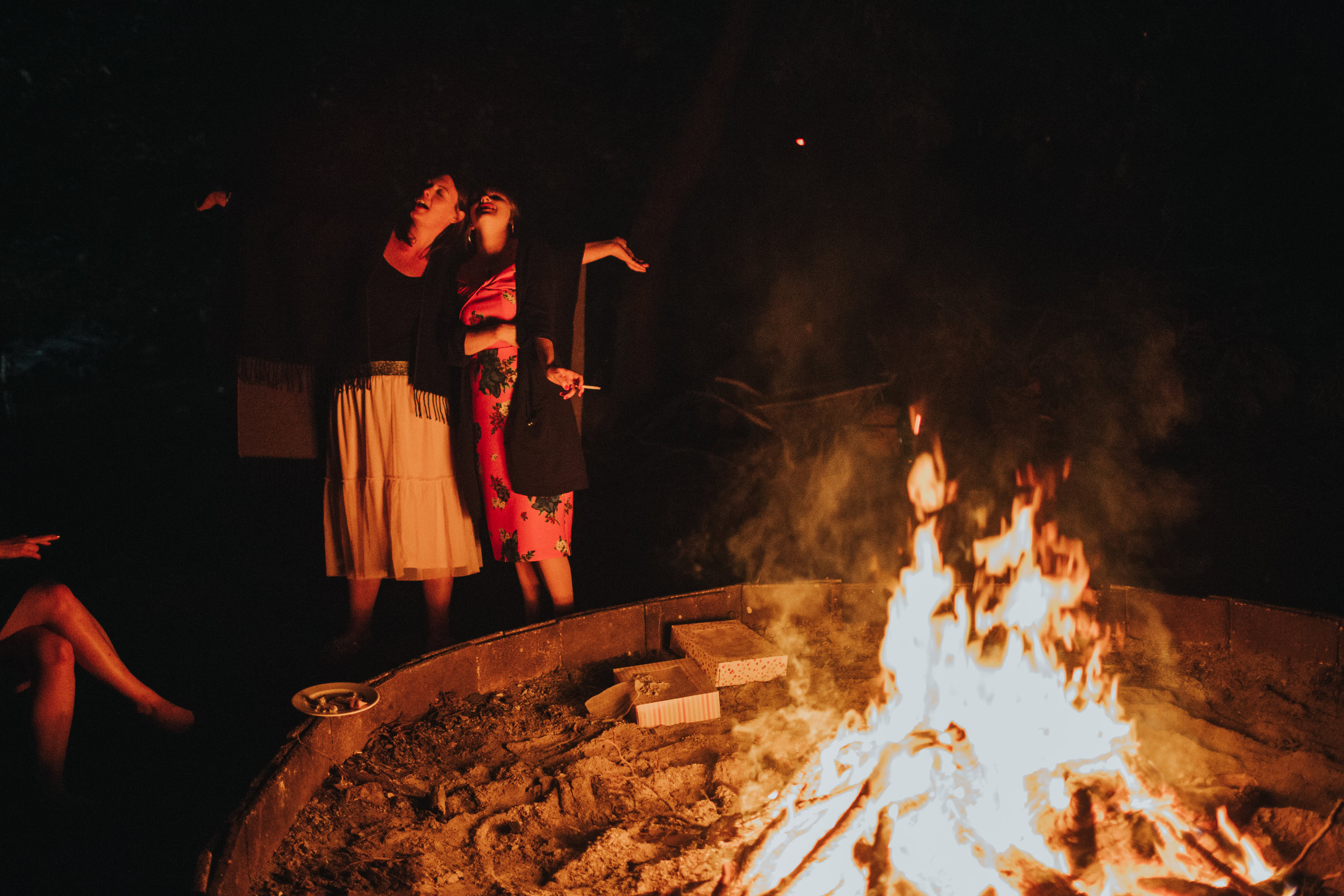 Two mildly inebriated weddings guests sing like wild animals at a campfire at someones wedding. 