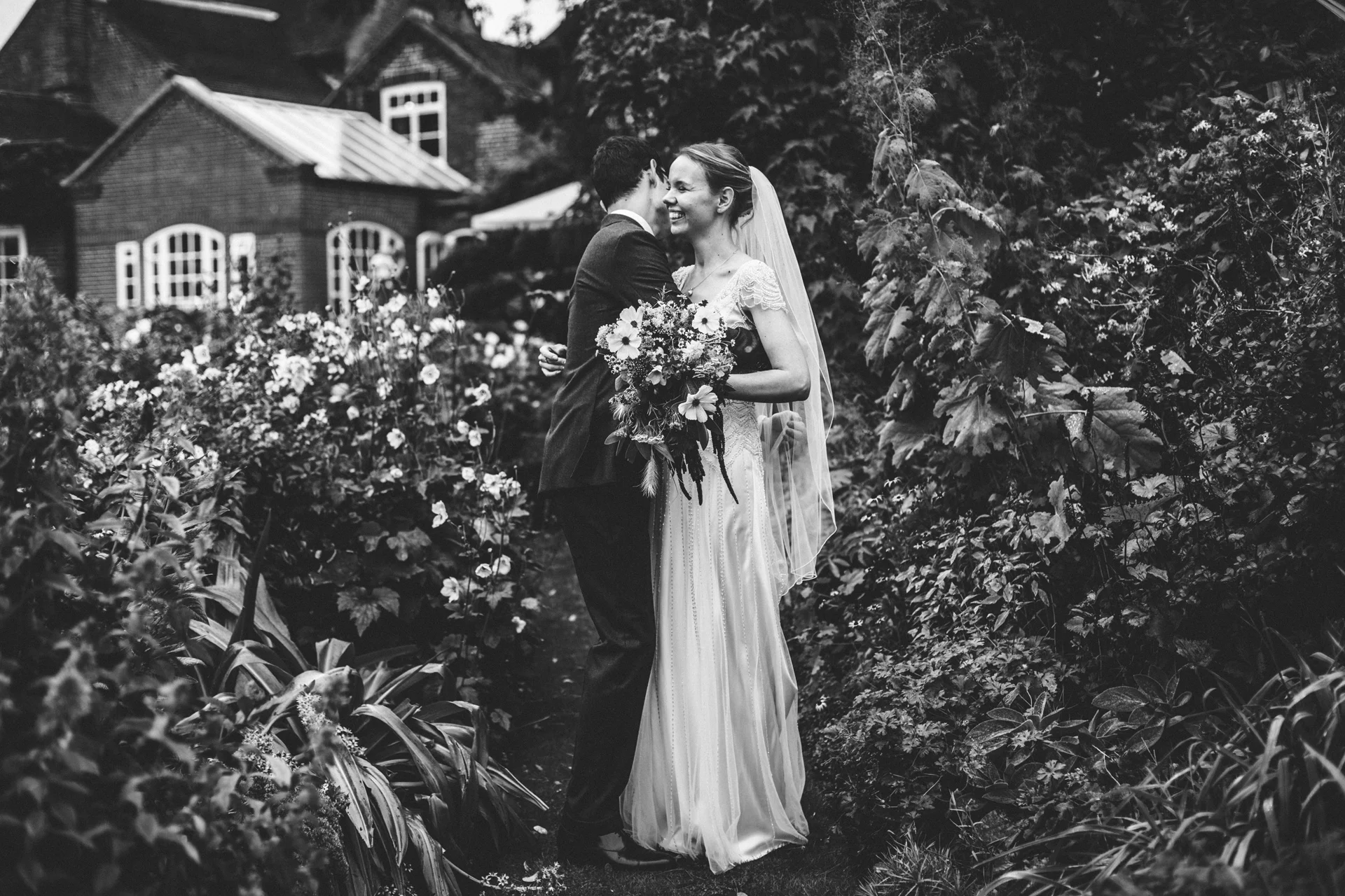 Couple laugh together on their wedding day at Goldstone Hall, Market Drayton. Photograph in black and white. 