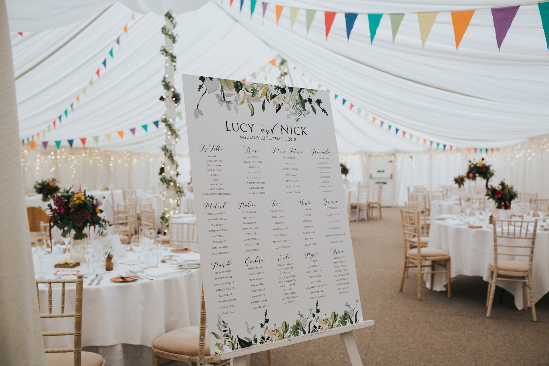 Table plan in marquee full of colourful flowers and bunting at Goldstone Hall. 