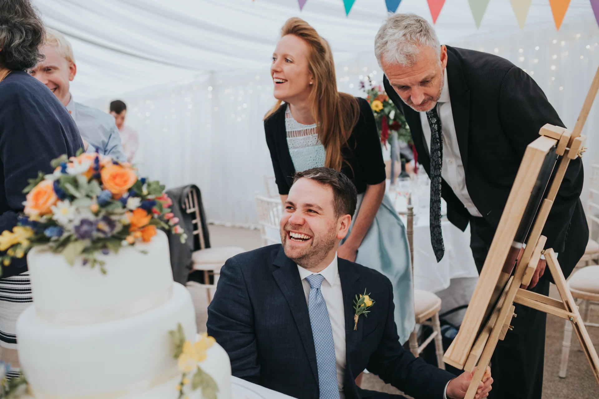 Guests laugh as they look at photographs together. 