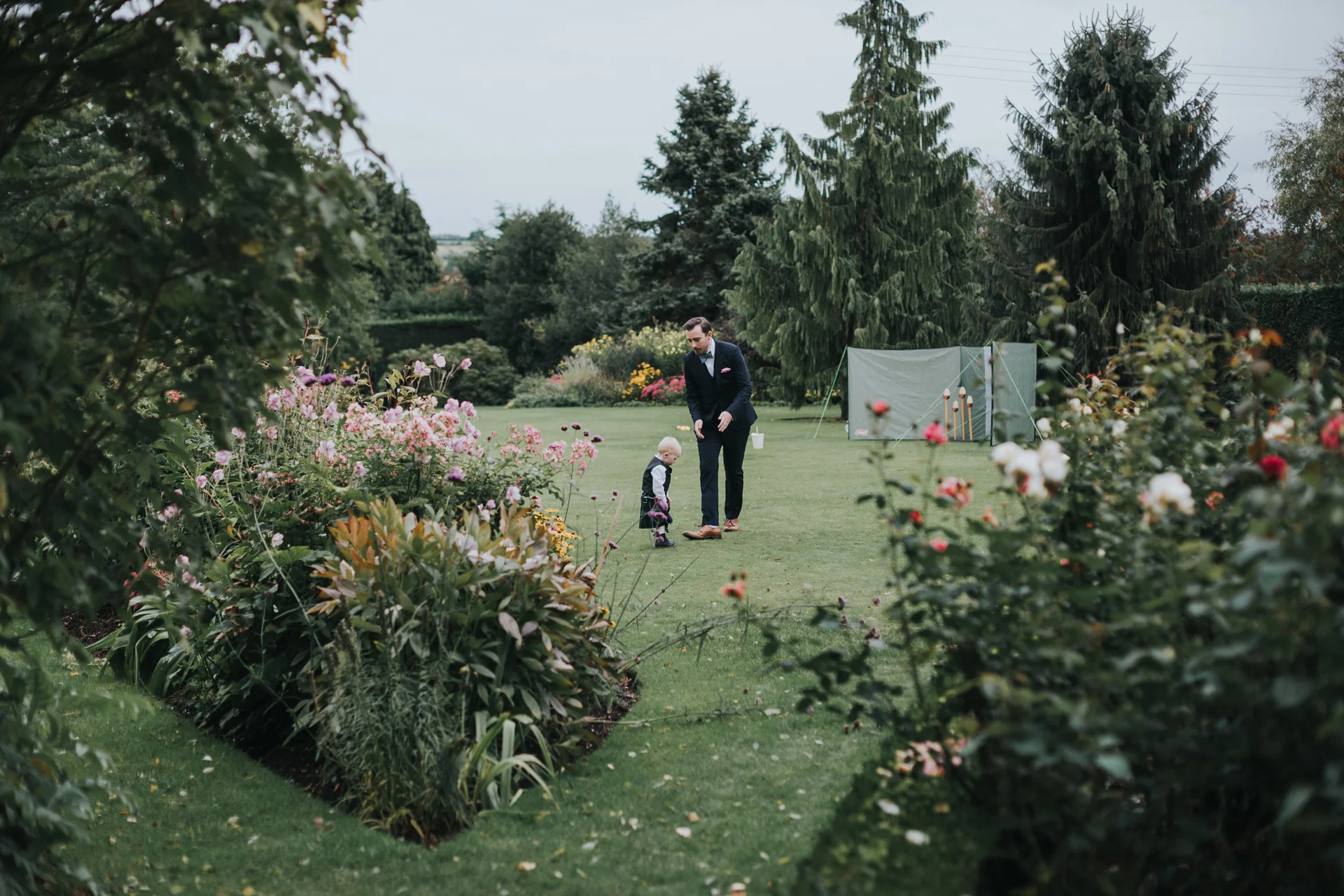 Toddler and his father play together in the garden. 