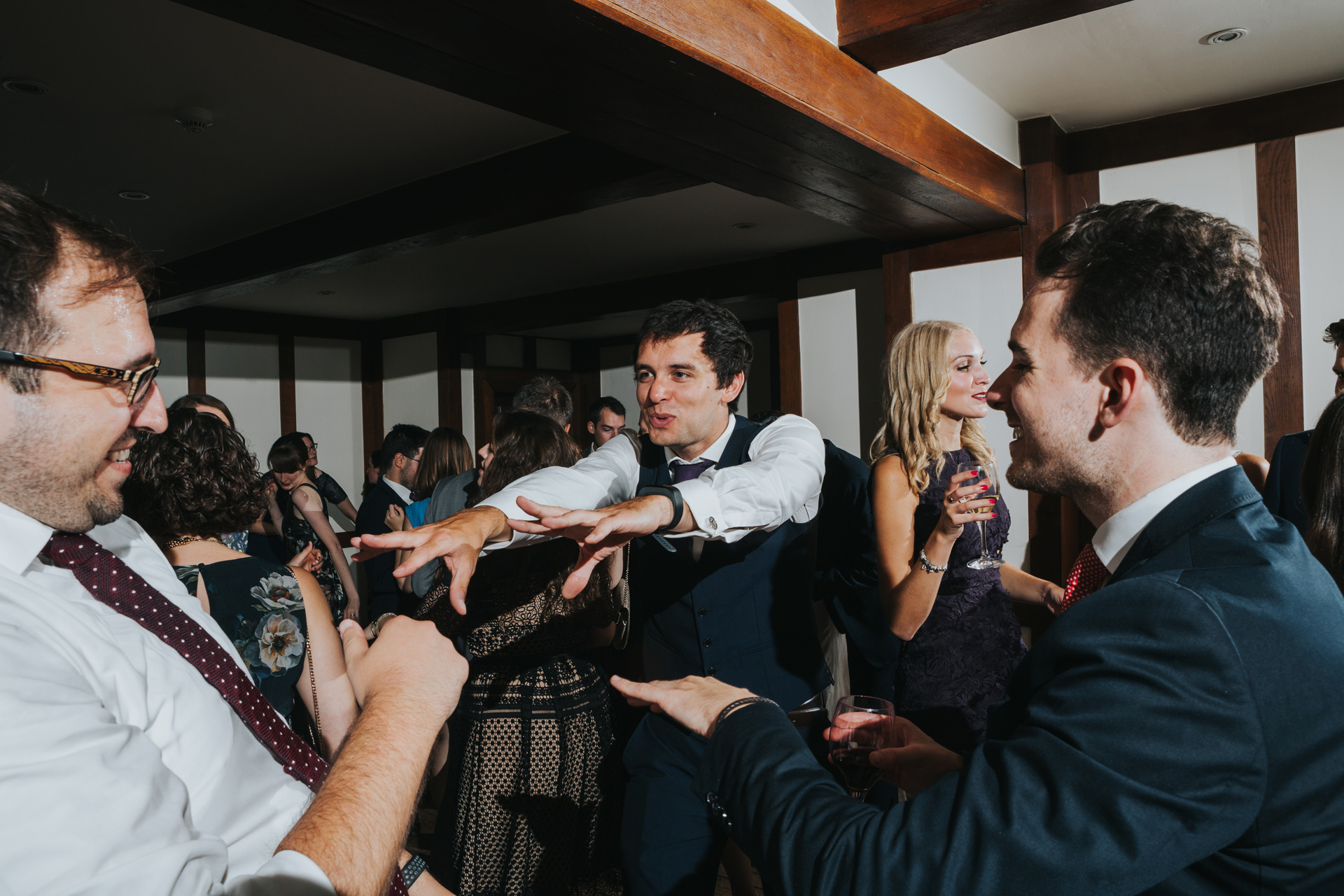 Male wedding guests throw out some stretchy arm dance moves. 