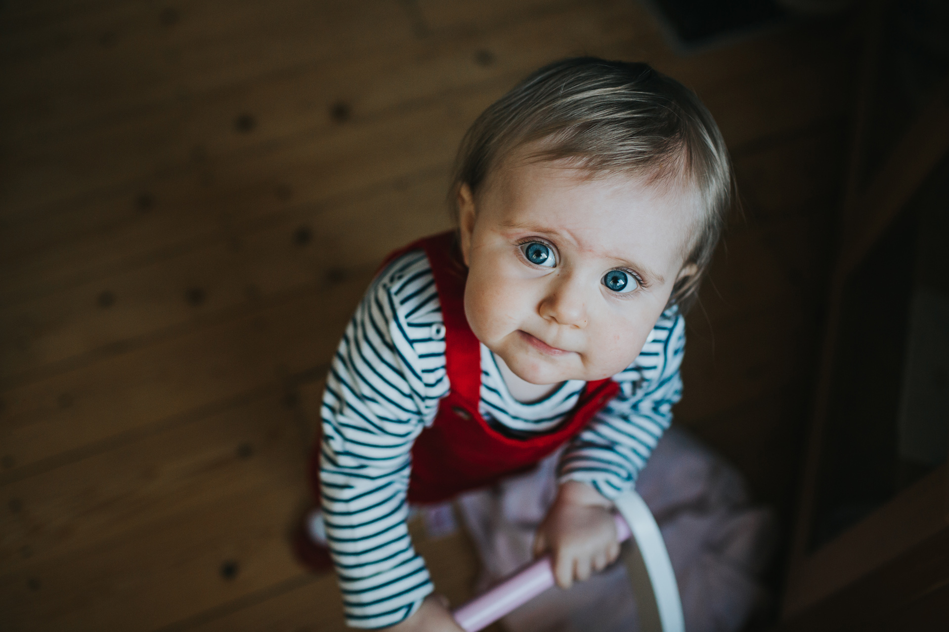 Little girl looks up at the camera with a curious look. It's her first birthday. 