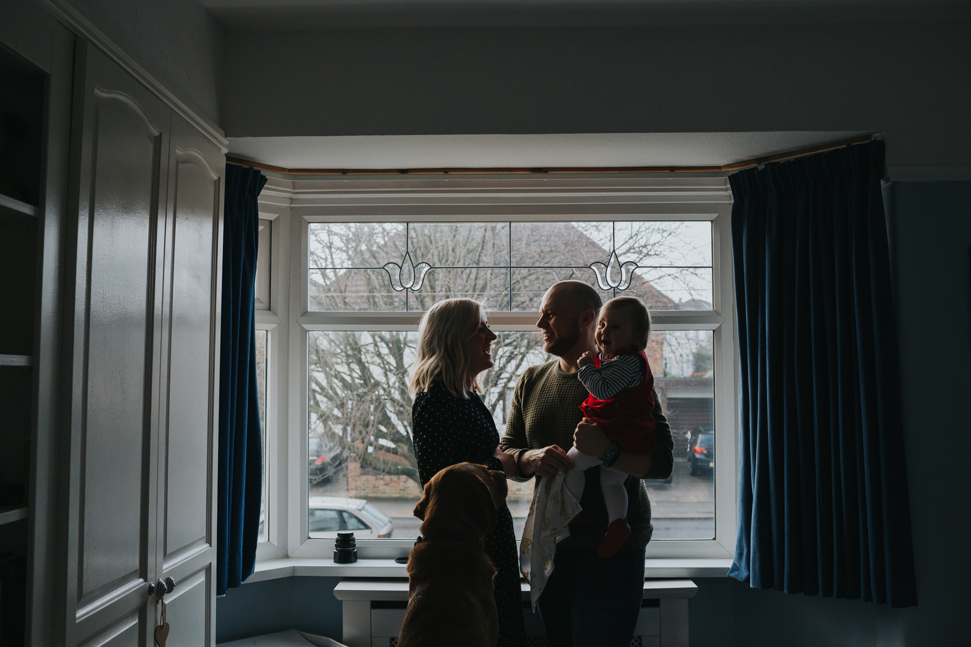 Silhouette of family standing together in front of the master bedroom window. 