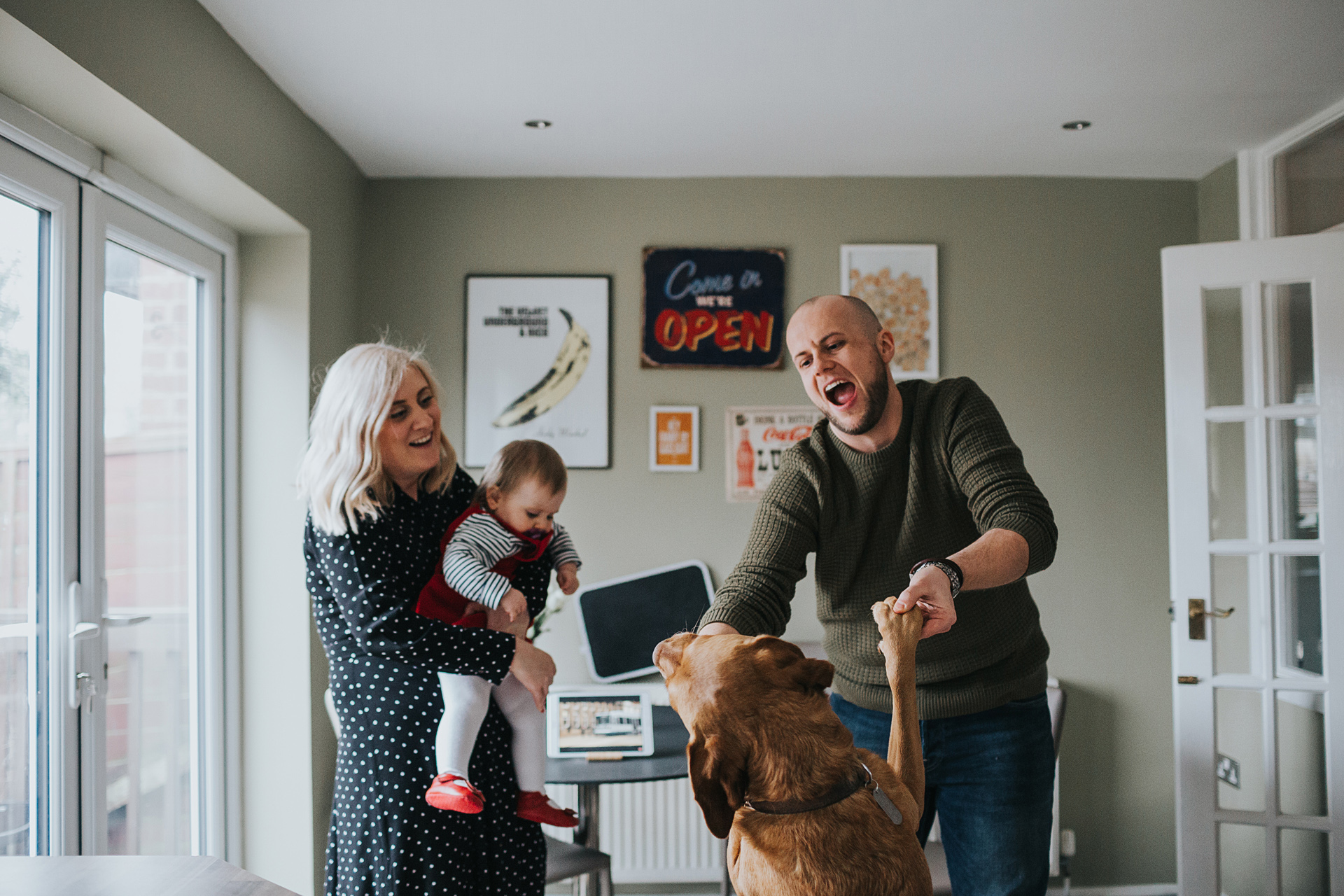 Family have a dance with the dog in the kitchen. 