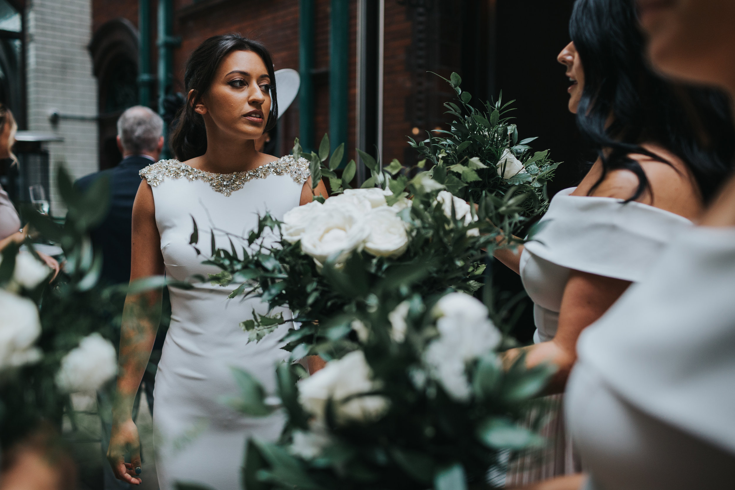The bride leaves her hotel to get to the church, surrounded by her bridesmaids beautiful white and green bouquets. 