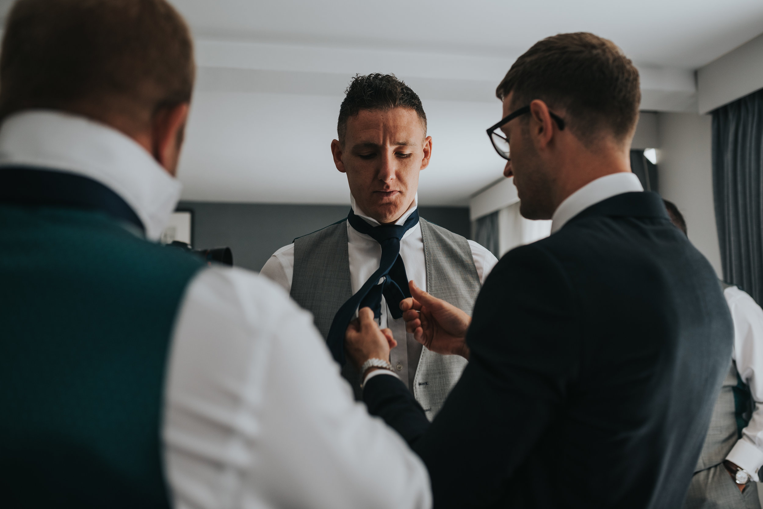 The groom fixes one of his groomsmen's ties. 