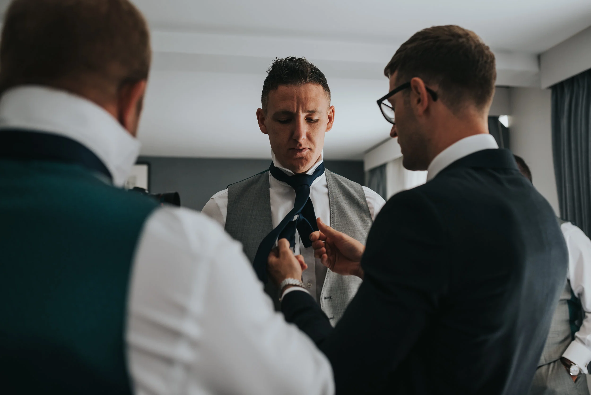 The groom fixes one of his groomsmen's ties.