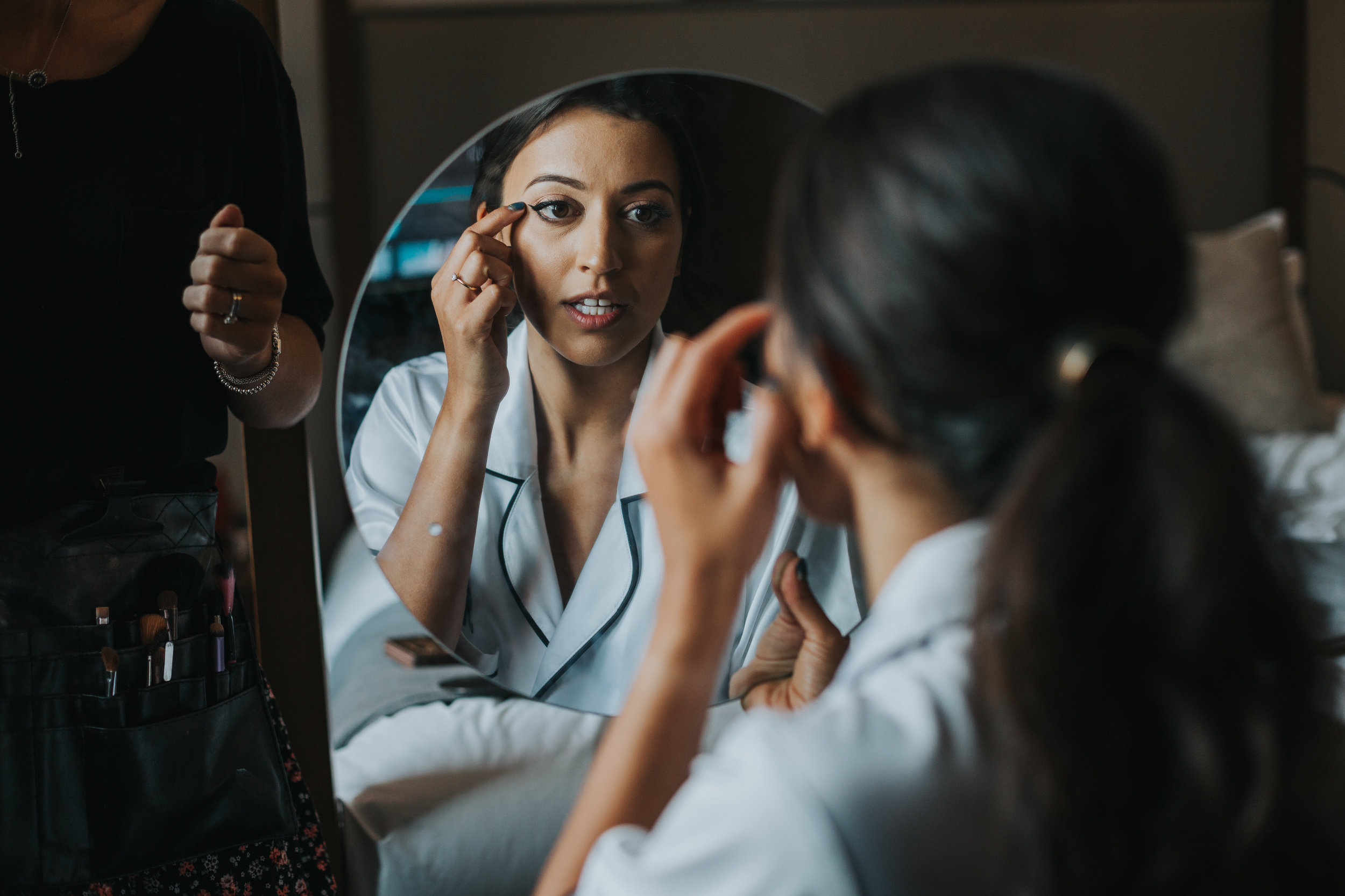 Bride looks at her makeup in mirror. 