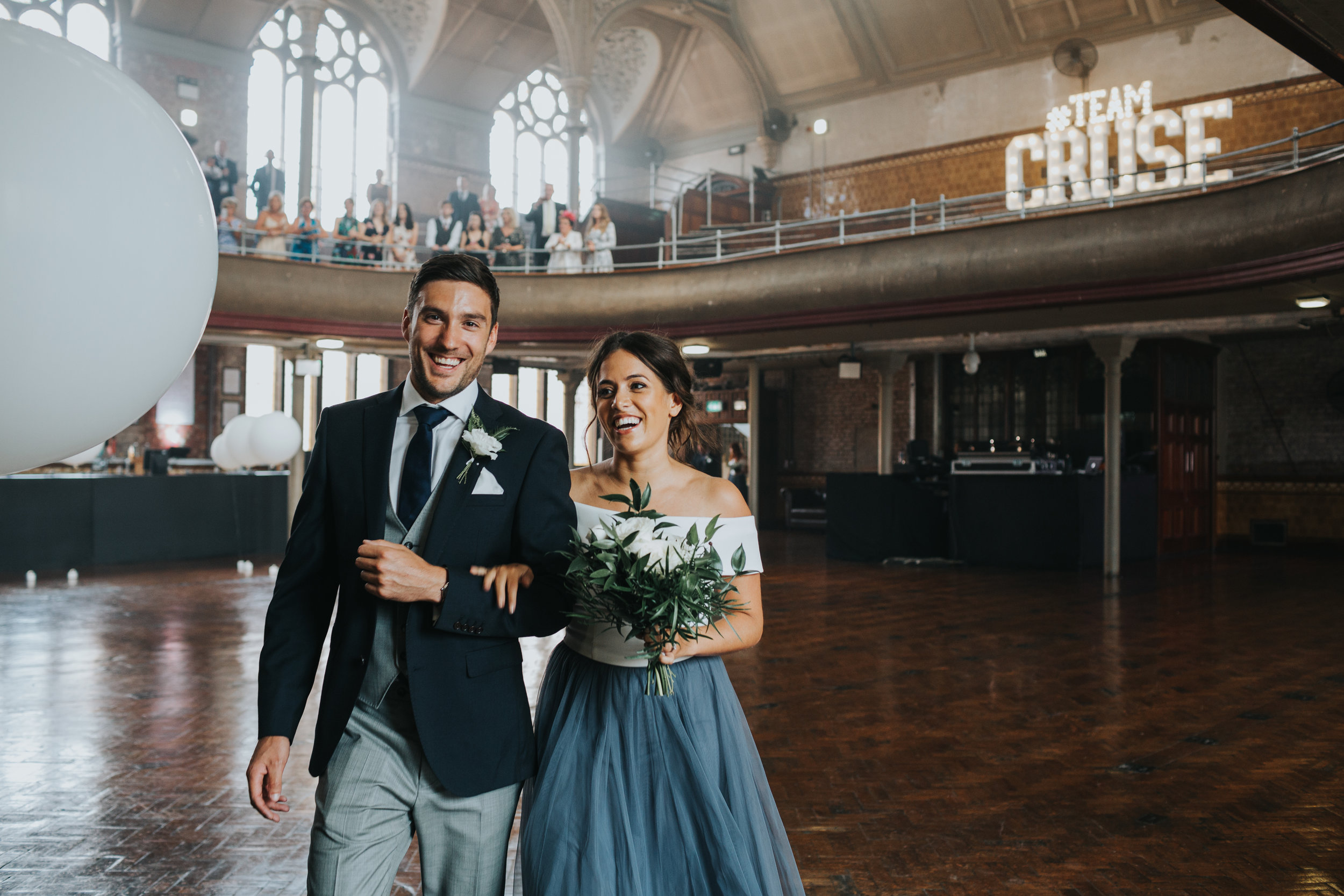 Another bridesmaid and groomsmen make their way across the hall laughing. 