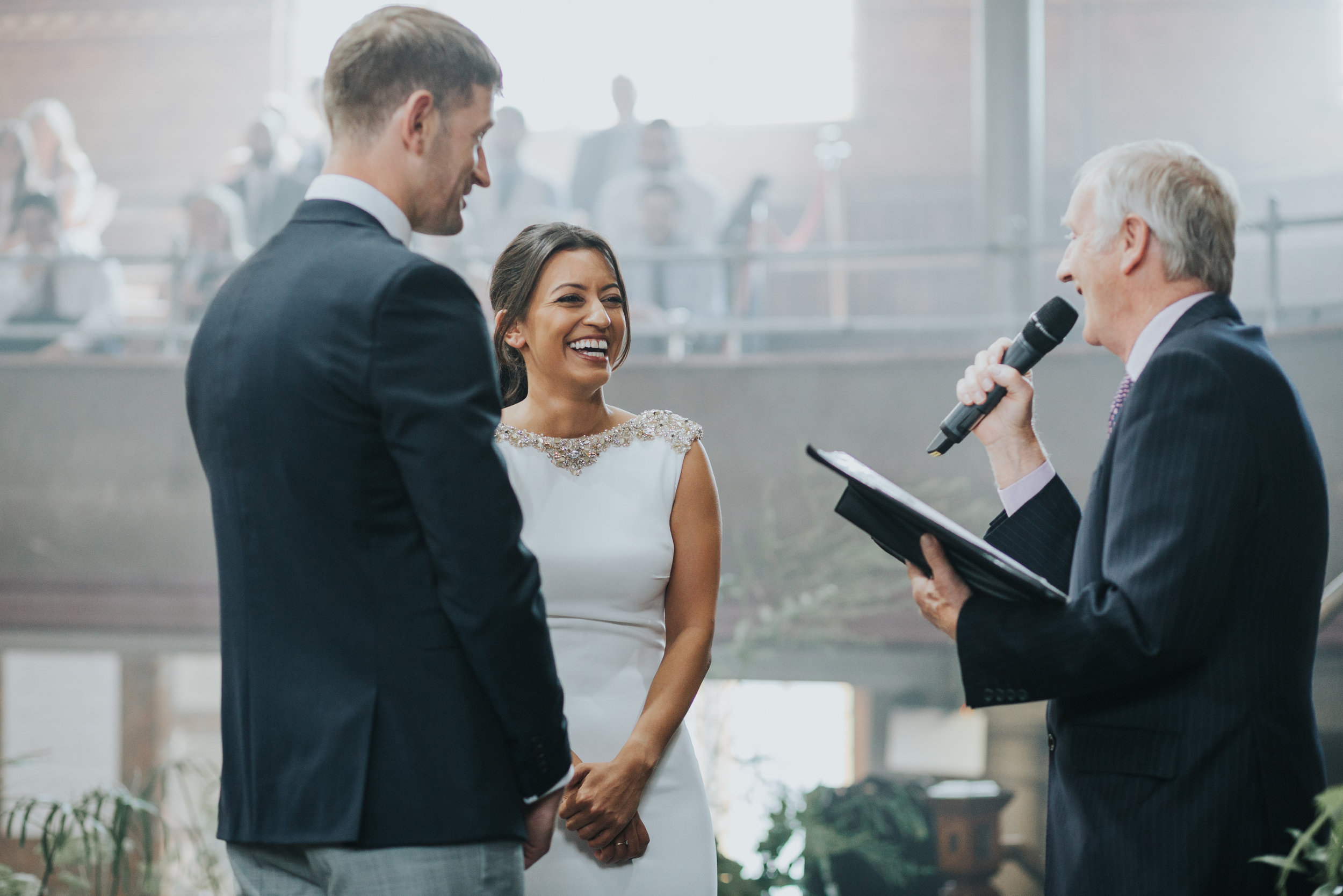 Bride laughing as the officiant makes a joke. 