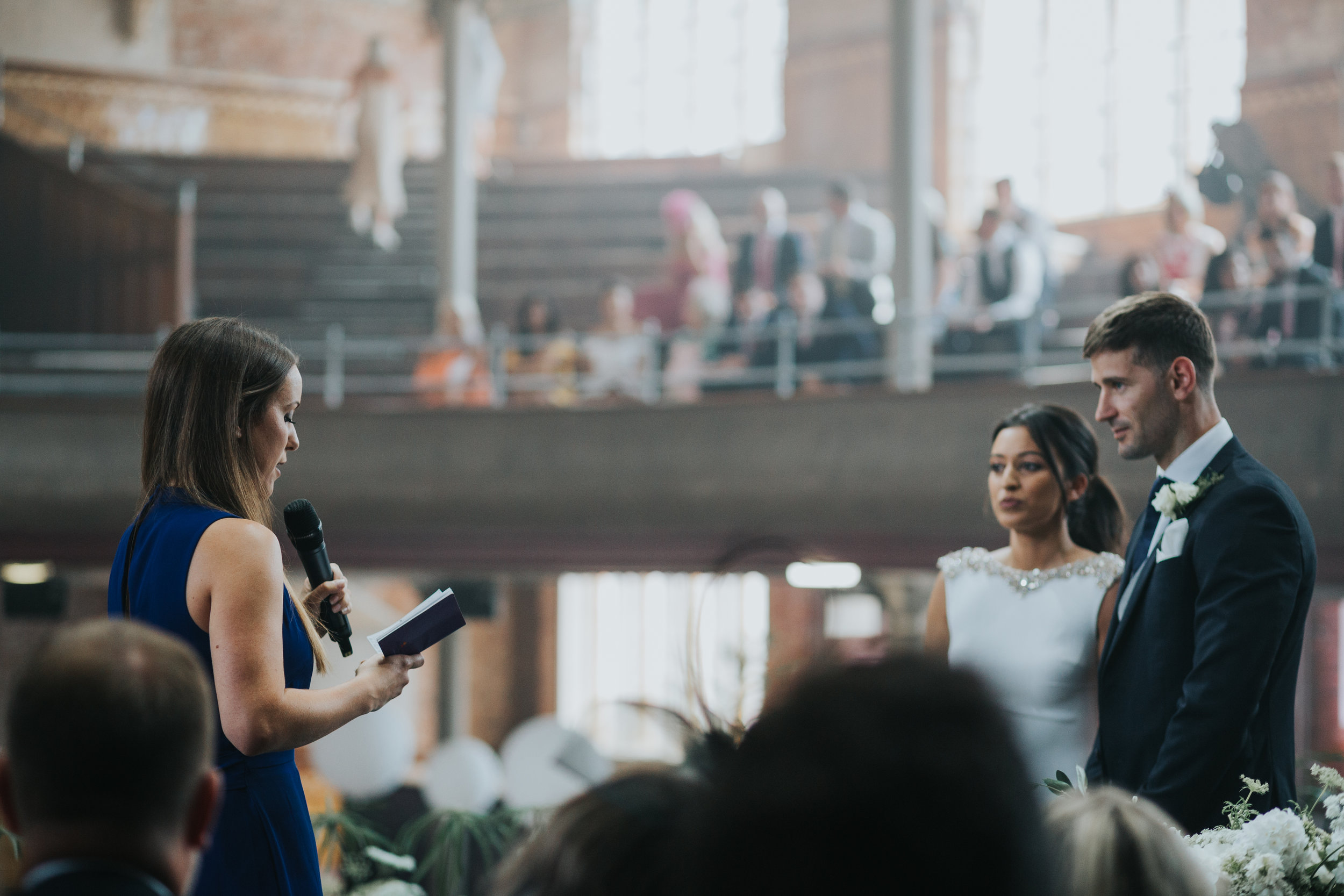 Bride and groom listen as friend gives a reading